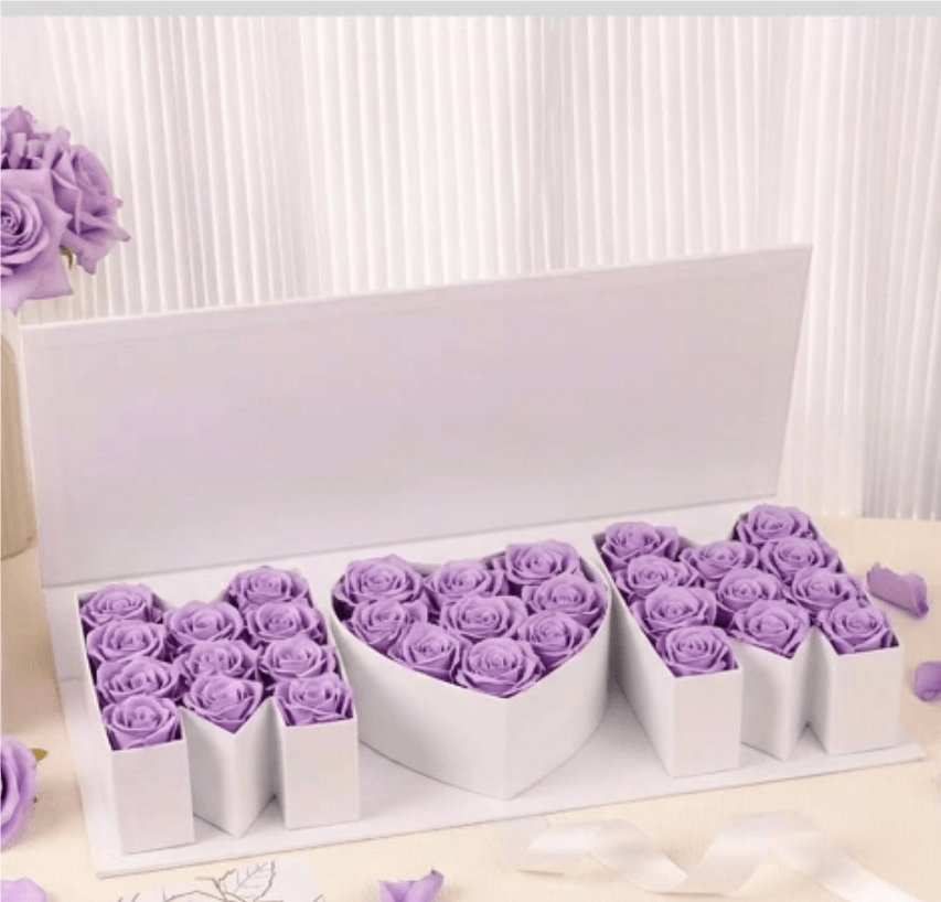 Mom’s Infinite Grace by The Flower Spot™ - Mom's Infinite Grace is a luxury roses gift set designed to make her feel adored. The presentation blends either lavender or red roses arranged in white presentation boxes, including a romantic heart-shaped box at the center.  Each rose has been curated by the designer and arranged with a personal touch, tied with white ribbon. For anniversaries, Valentine's Day, Mother's Day, or any moment you want her to feel truly seen, this set sends a message of deep appreciation and timeless grace.  Feel free to mention the rose color during order submission. Box size: 16.9" x 7' x 2.5'