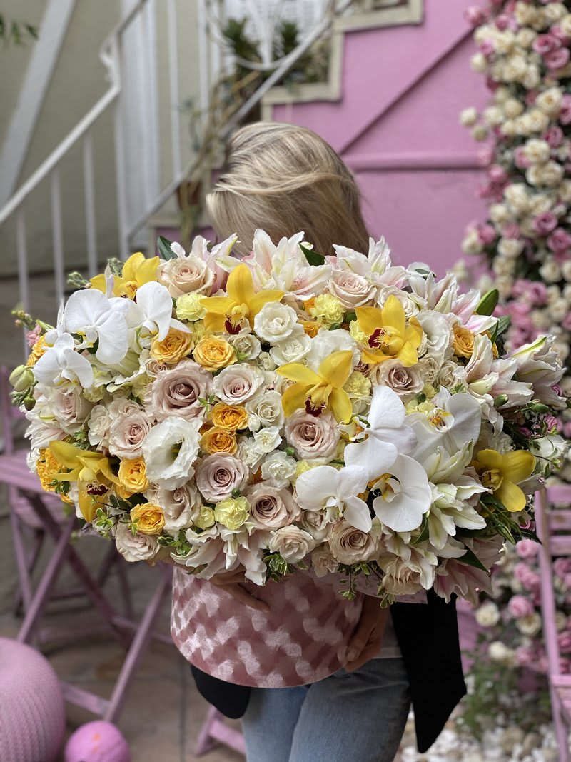 Large bouquet of white, cream, and yellow flowers held by a person