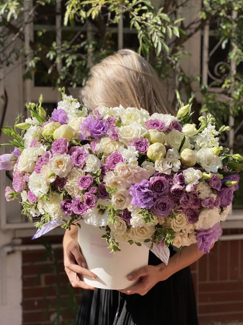Large bouquet of purple, white, and cream roses in a white box