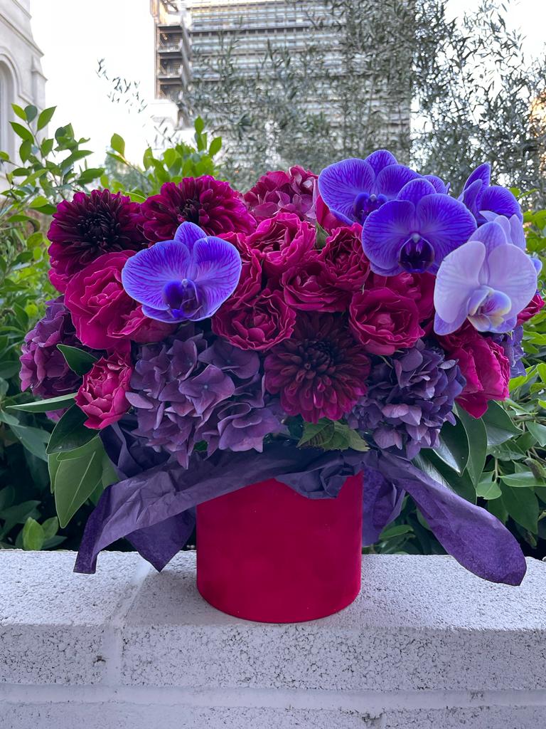 Bouquet of purple and magenta flowers in a red box