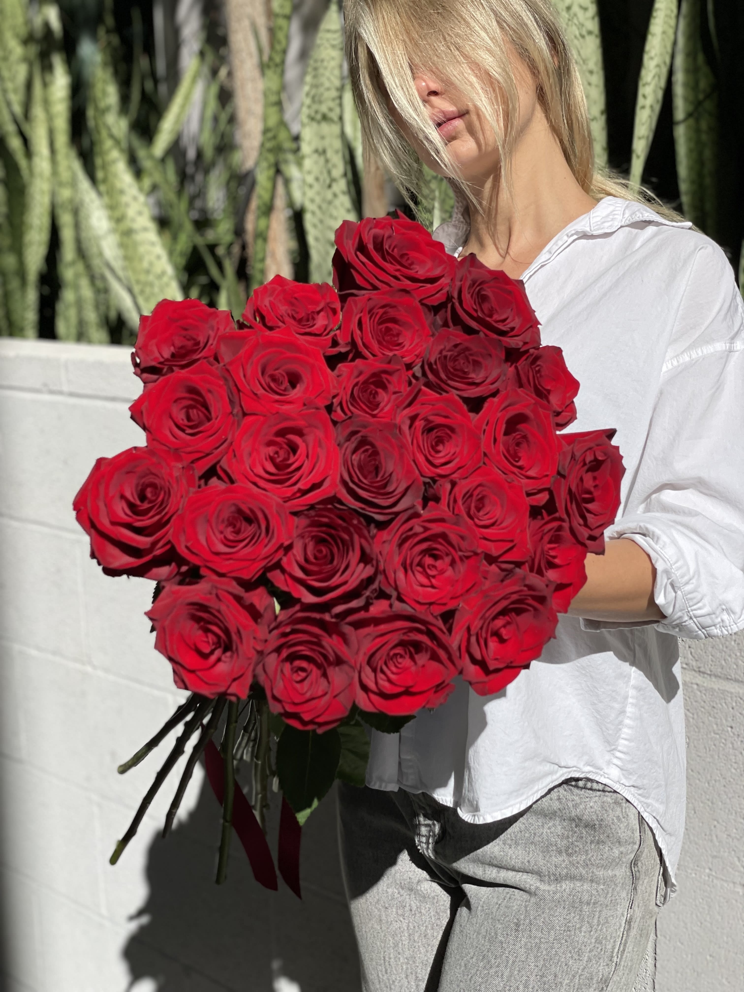 Woman holding a large bouquet of red roses