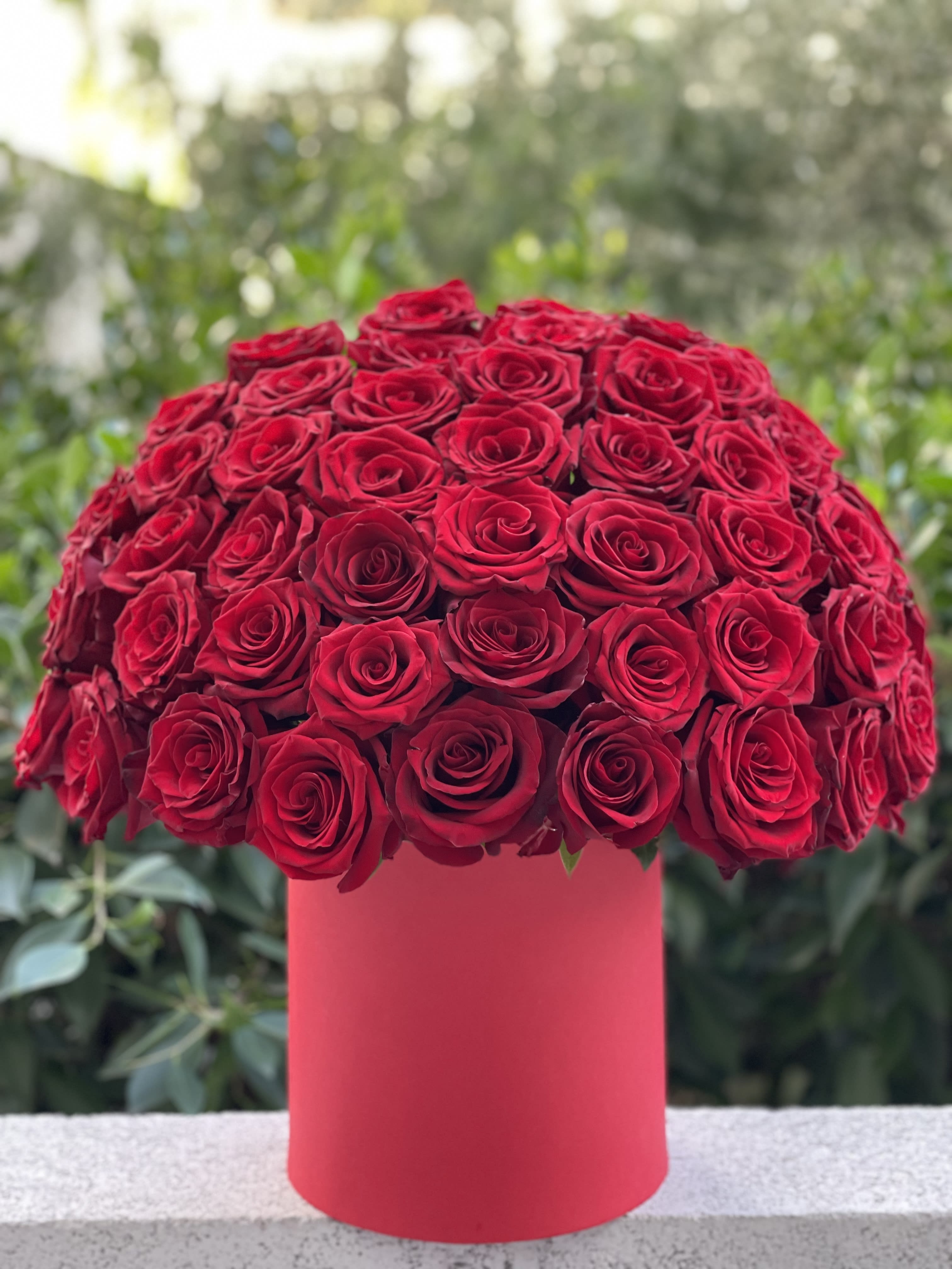 Round bouquet of red roses in a pink cylindrical box