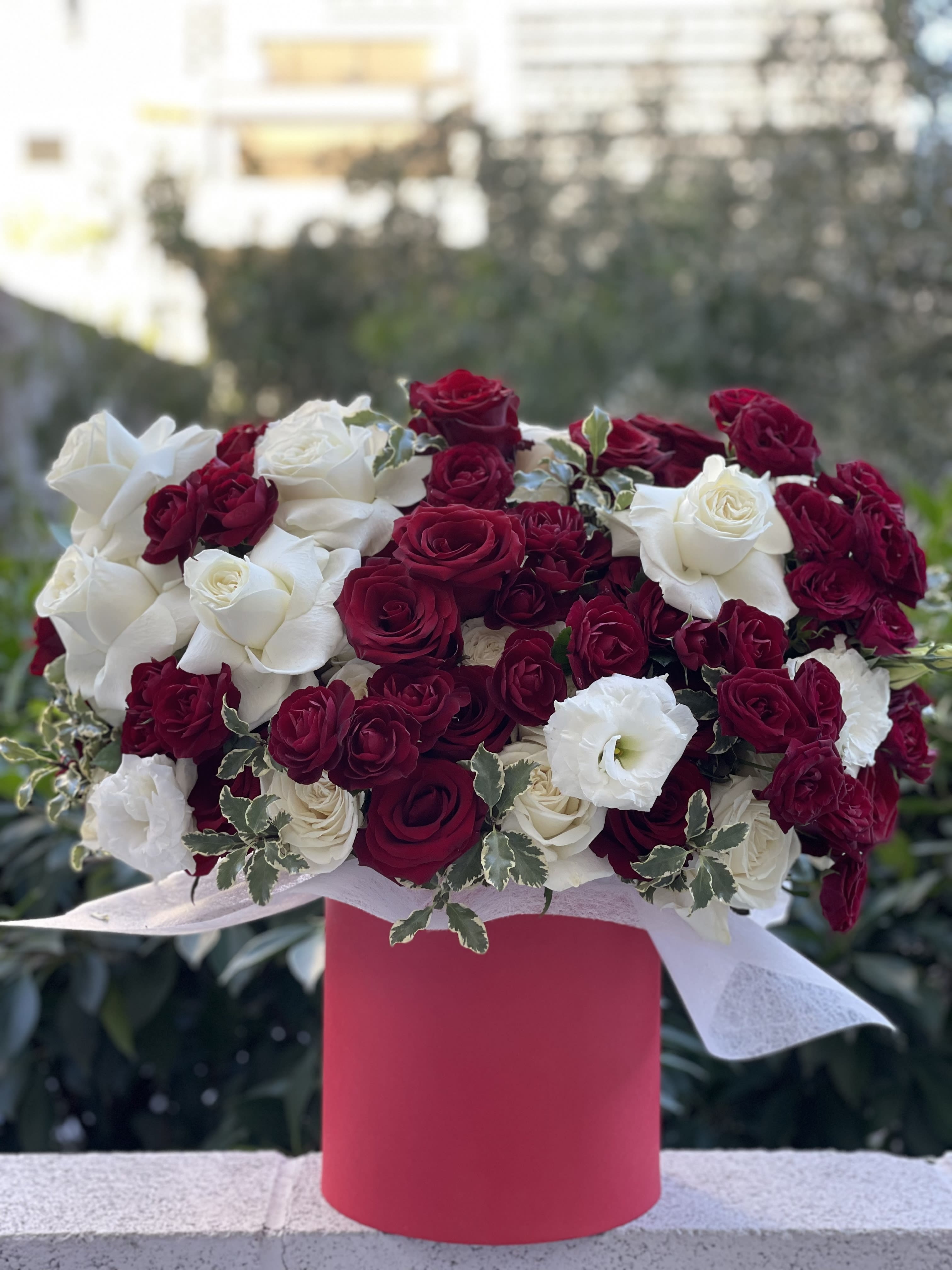 Red and white rose arrangement in a pink box