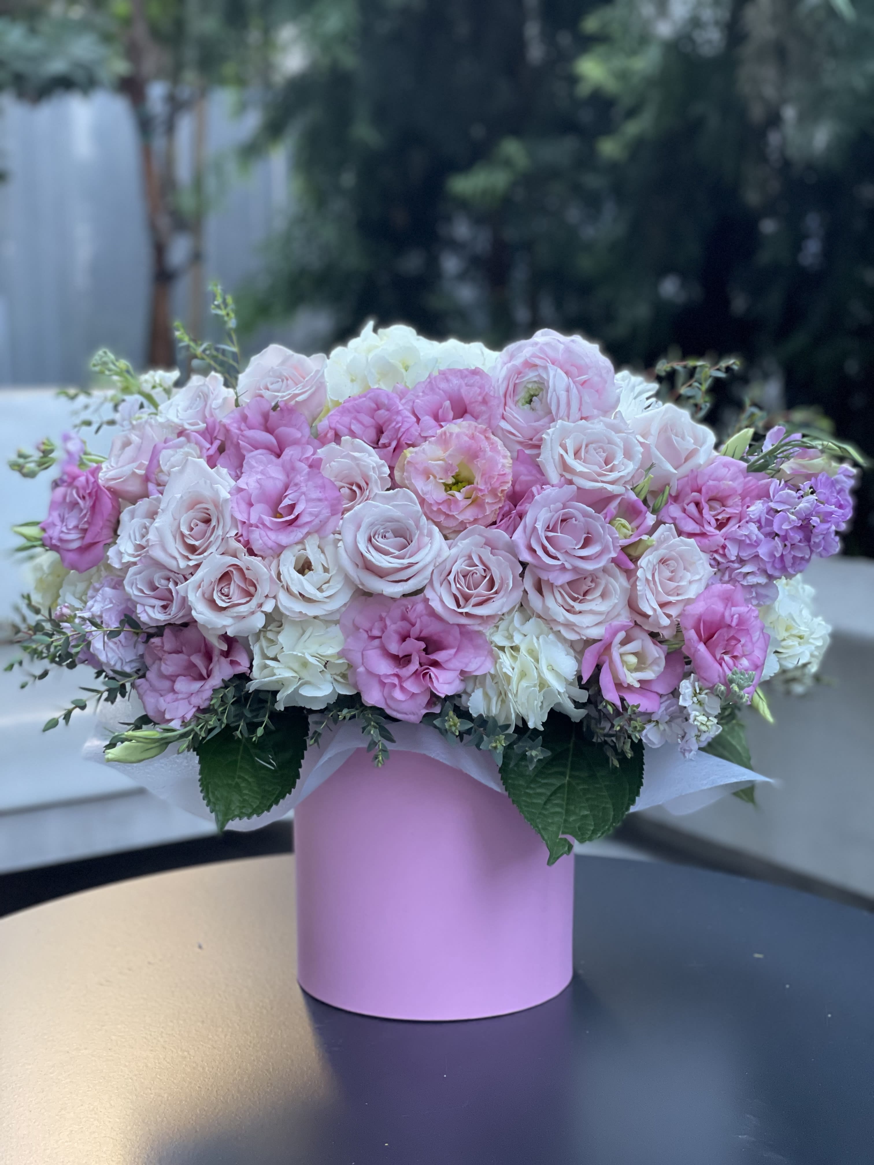 Pink and white roses arranged in a pastel pink box
