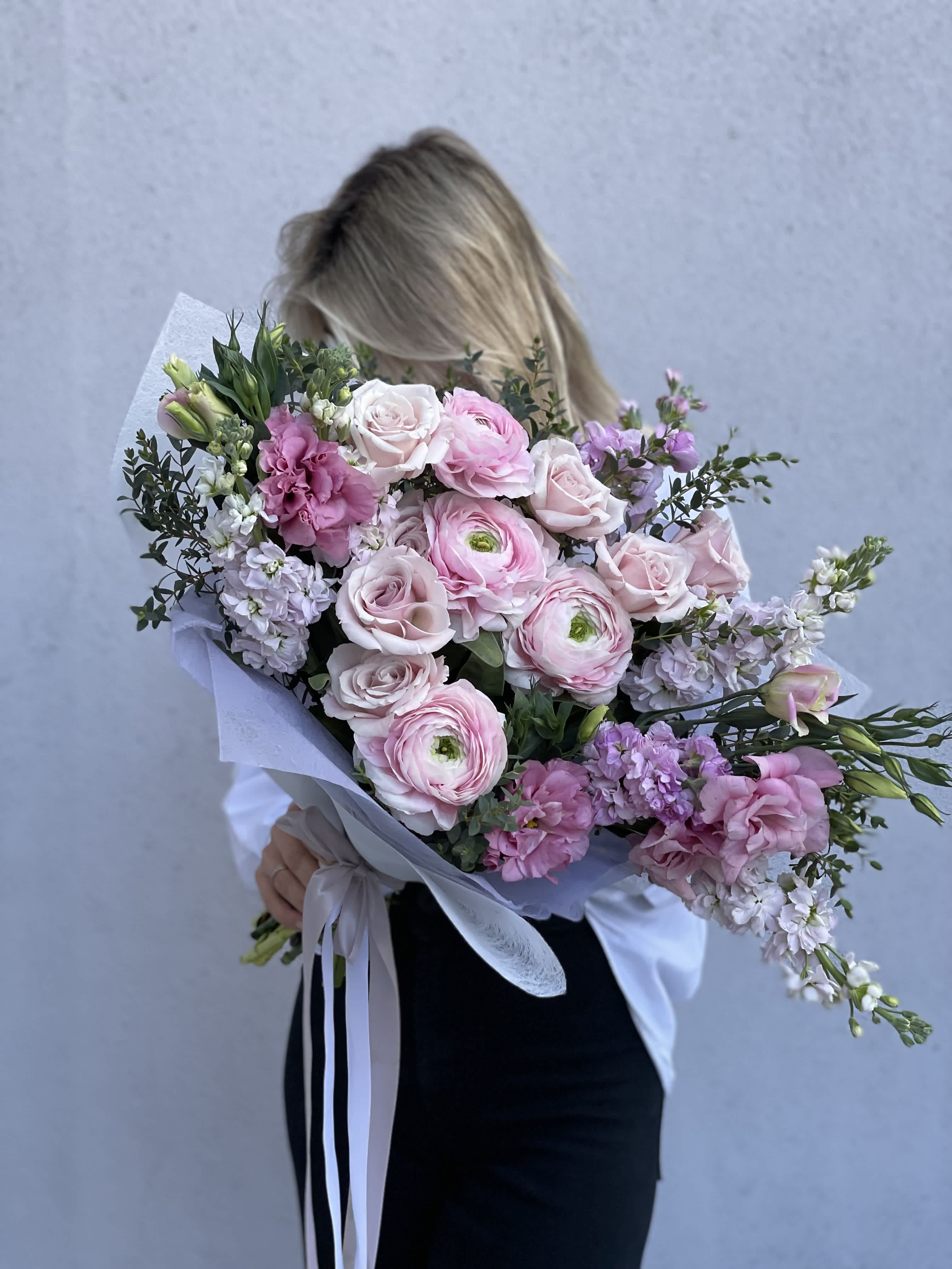 Woman holding a large bouquet of pink and white flowers