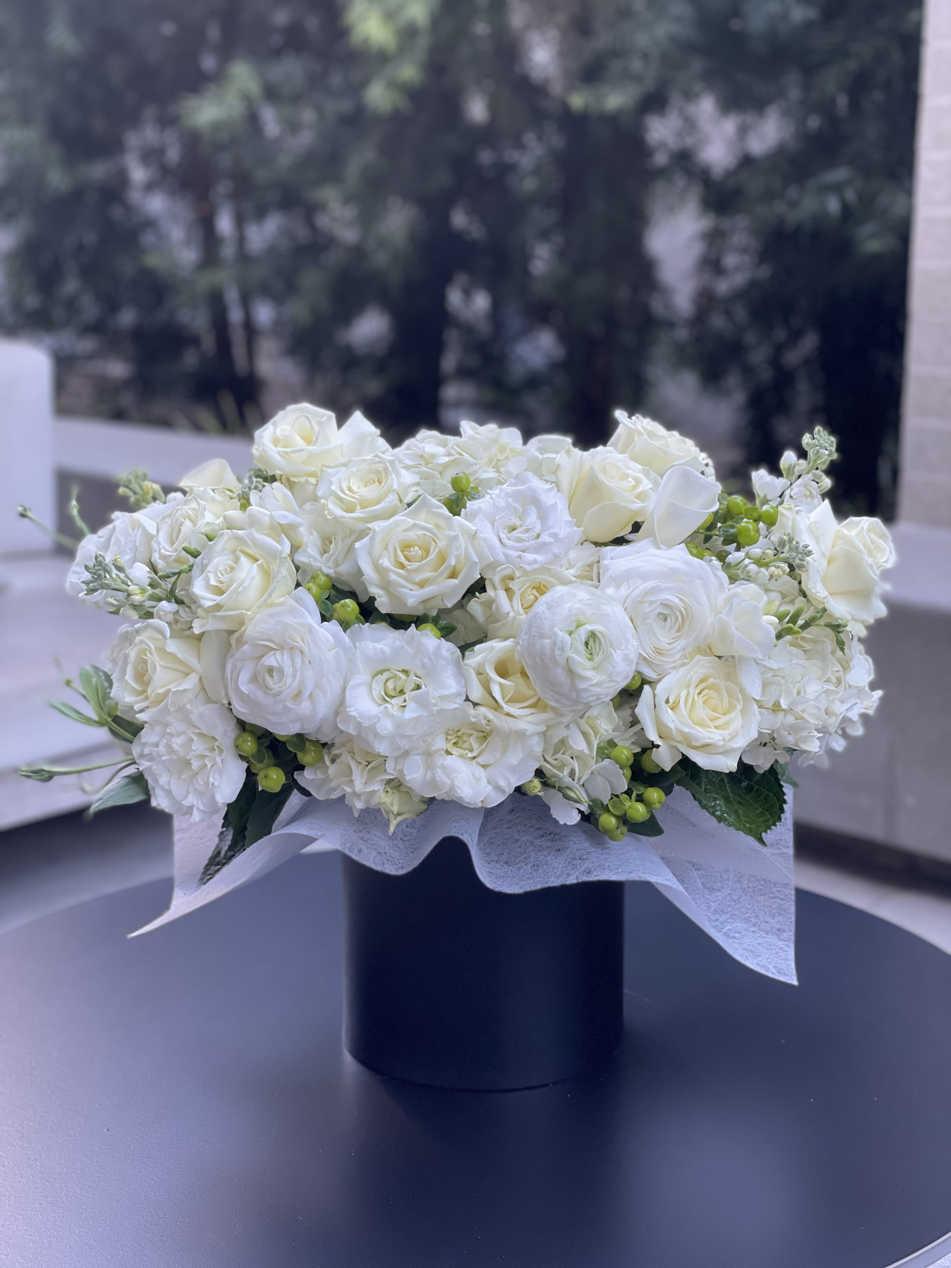 White rose and ranunculus arrangement in a black box