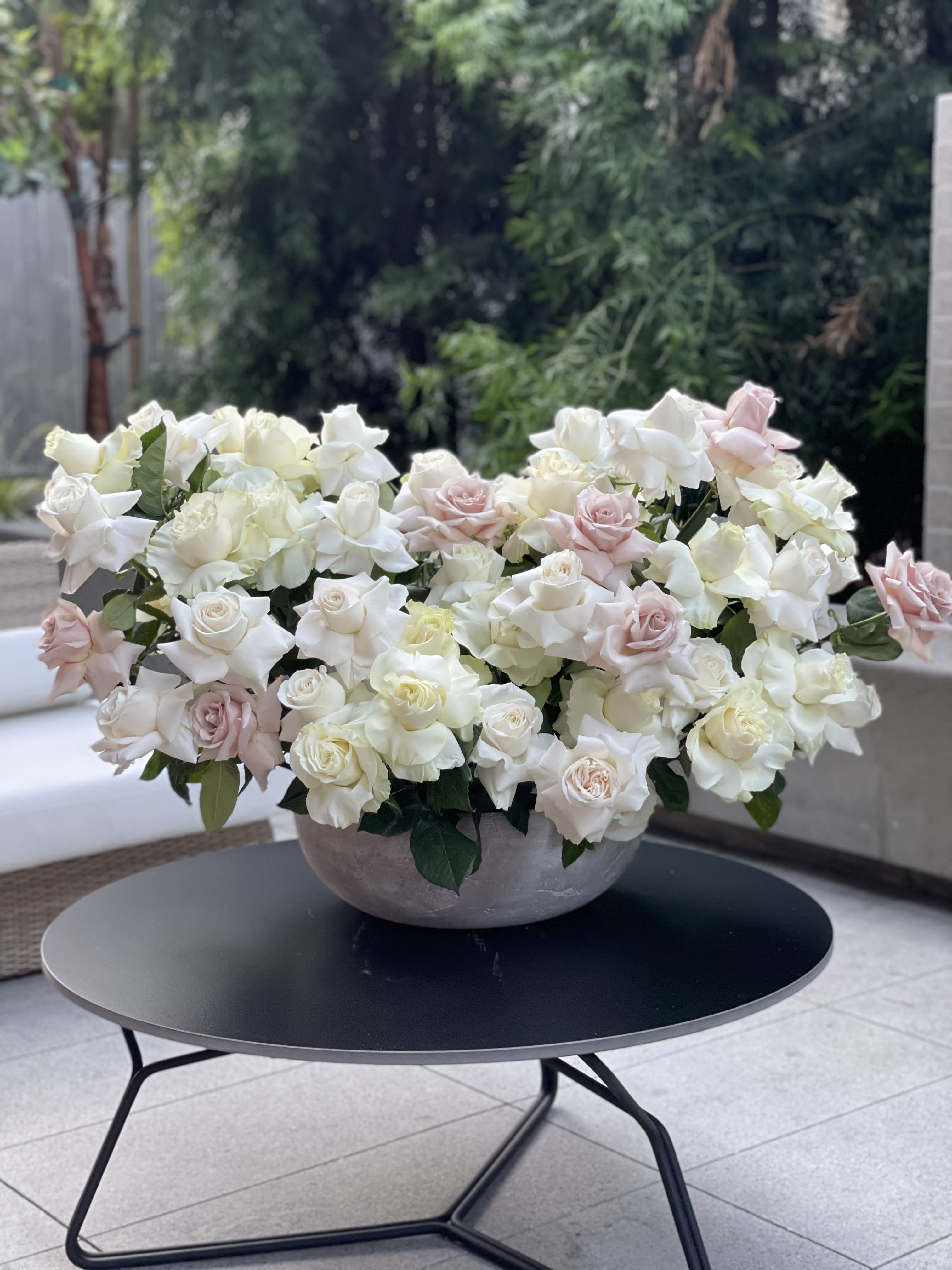 Large bowl arrangement of white and blush roses on a table