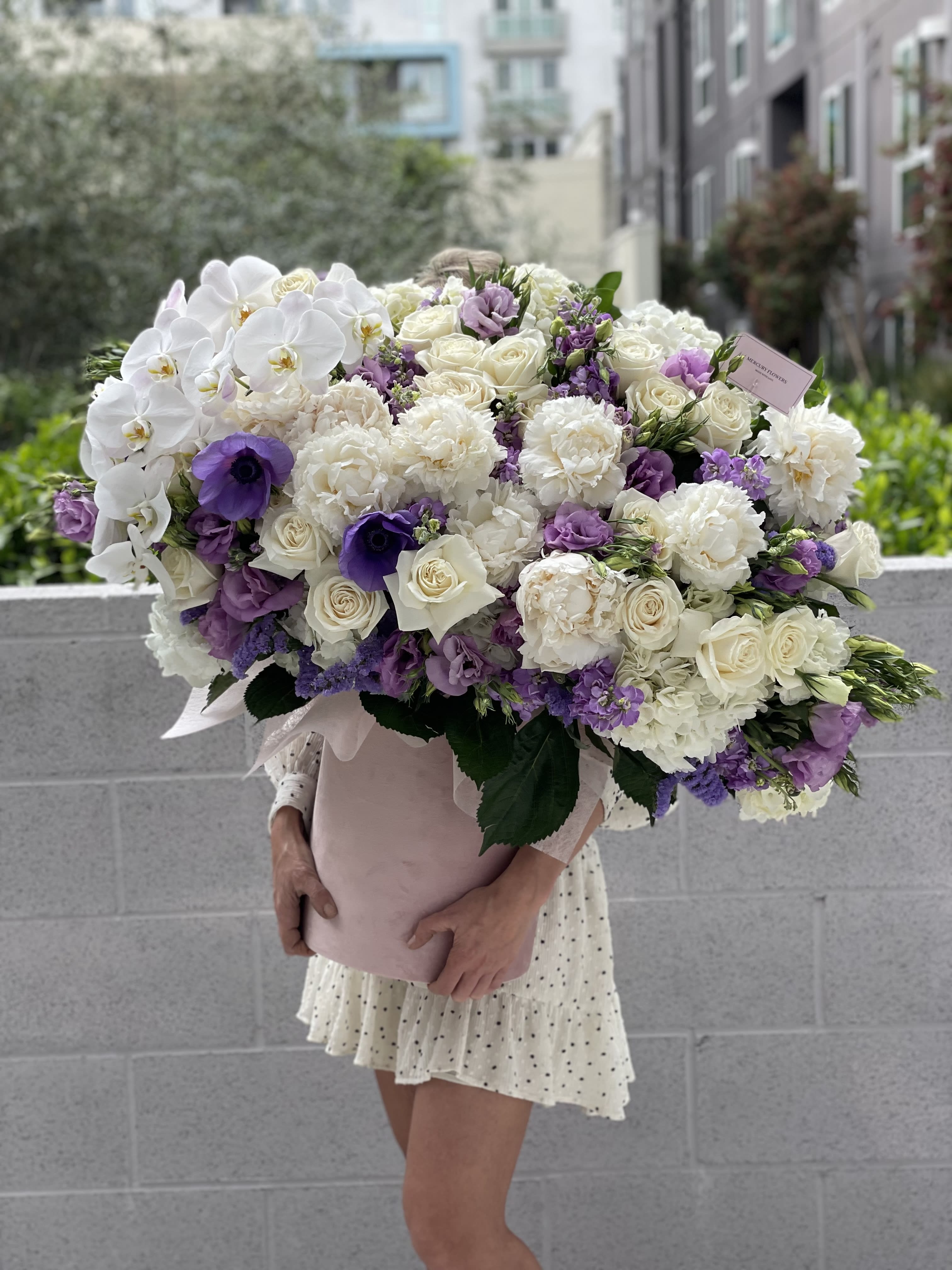 Large bouquet of white and purple flowers wrapped in pink paper
