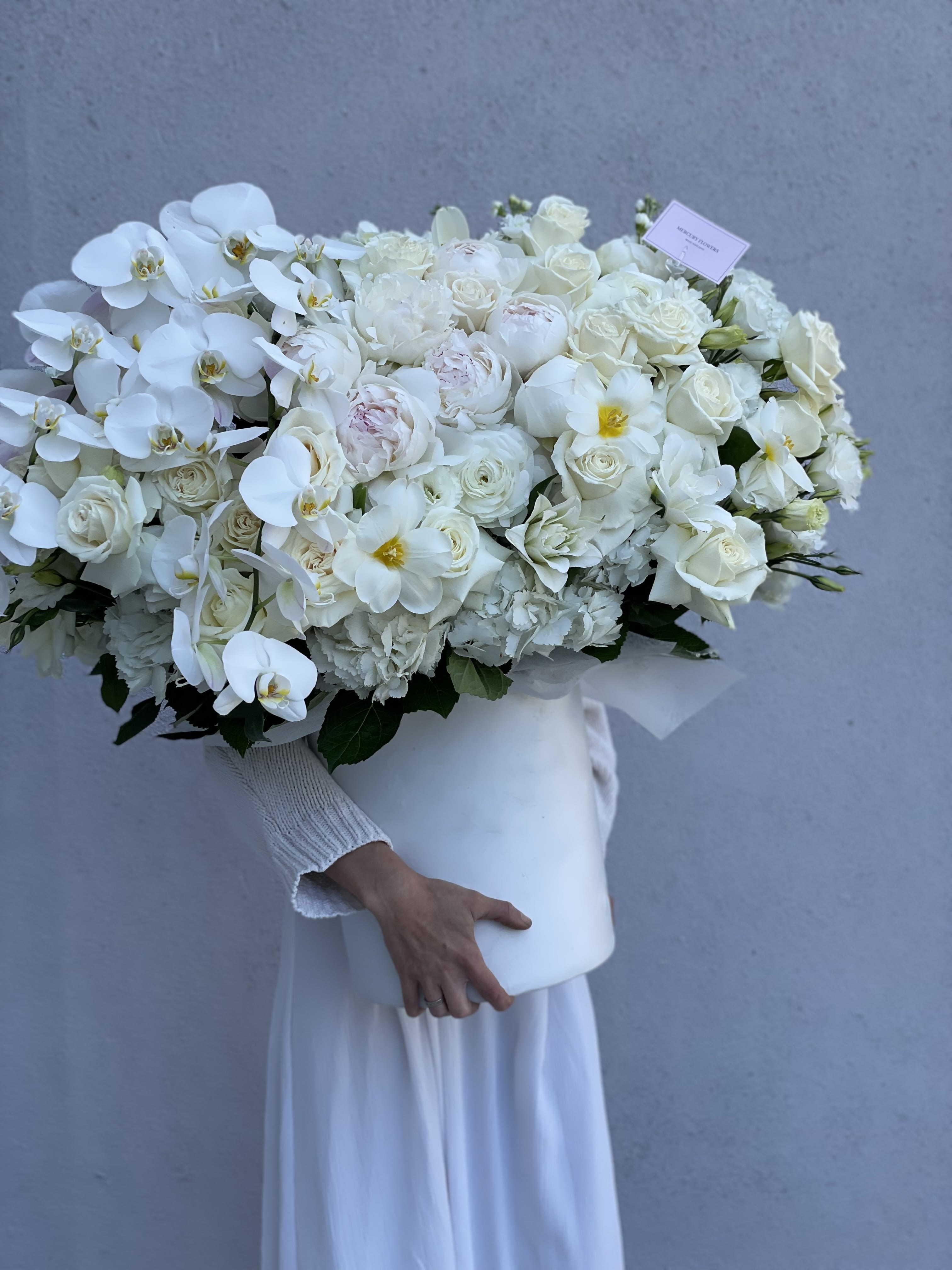 Large white bouquet with orchids and roses in a white box