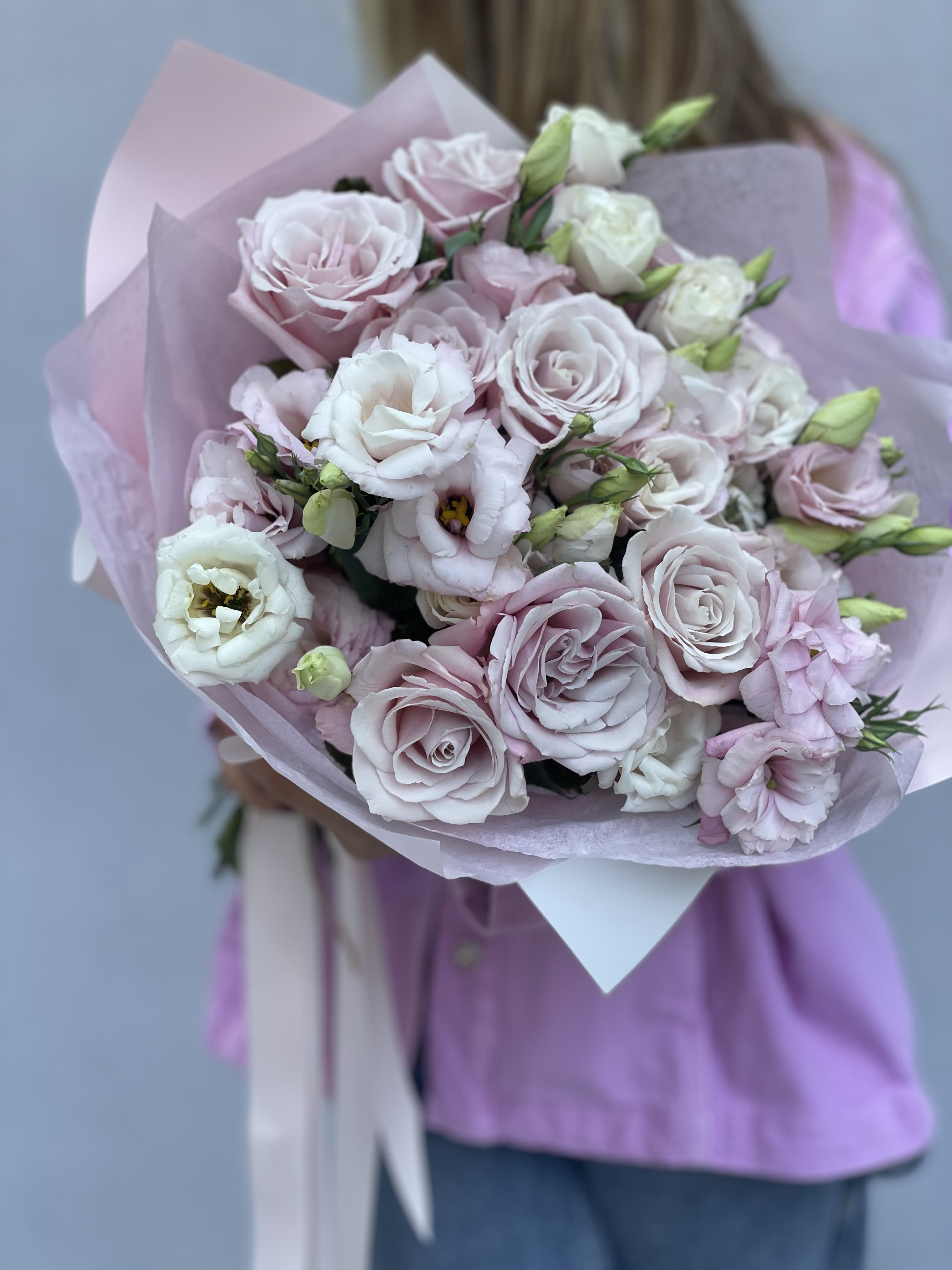Bouquet of pale pink and white roses wrapped in lavender paper
