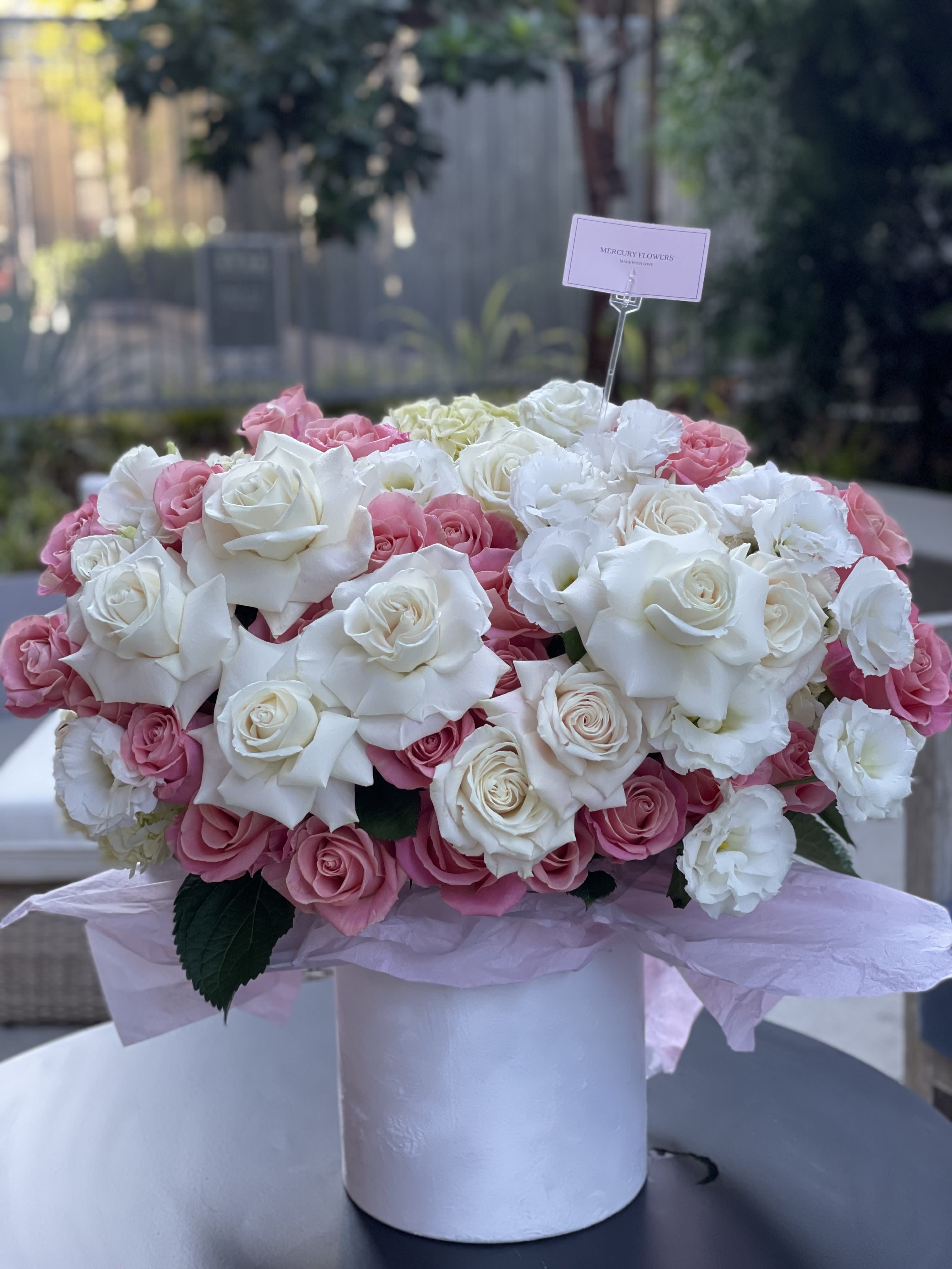 Pink and white rose arrangement in a white hatbox