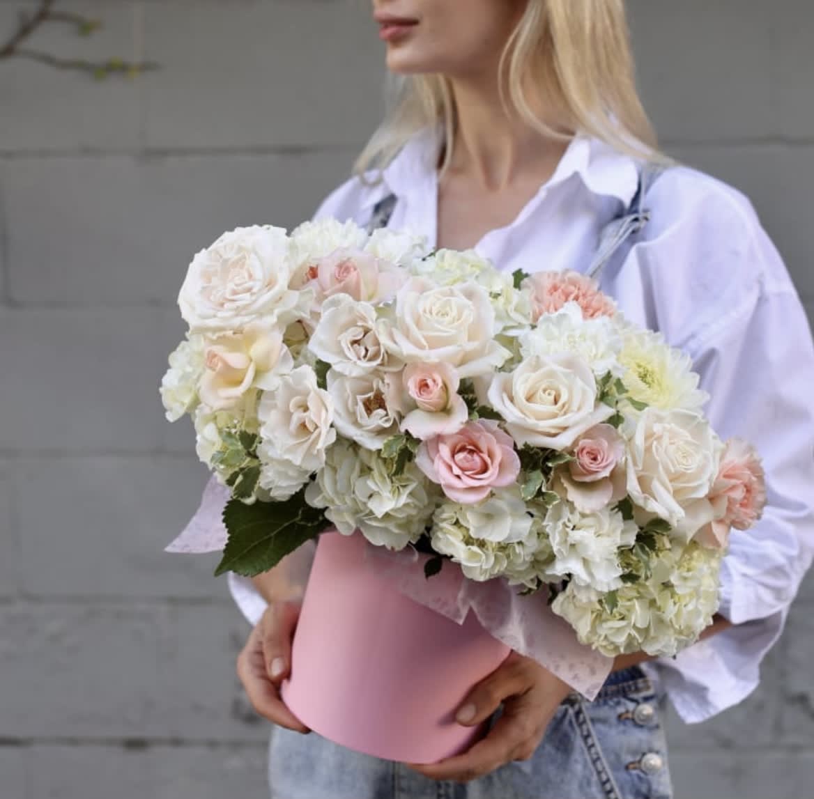 Woman holding a pink box of white and blush roses and hydrangeas