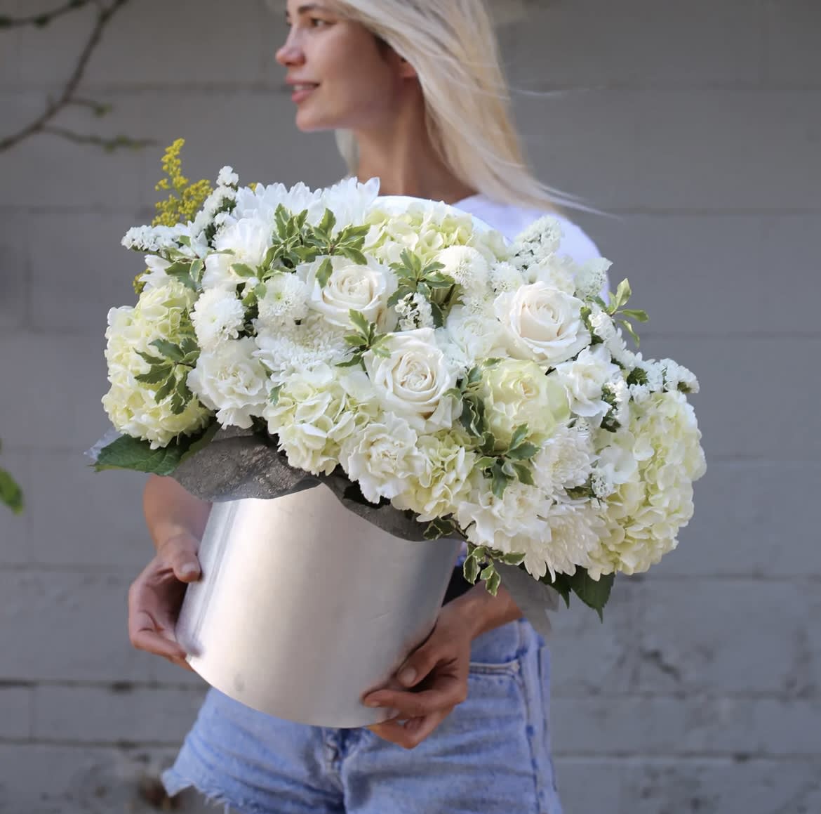 Woman holding a large white floral arrangement in a silver box