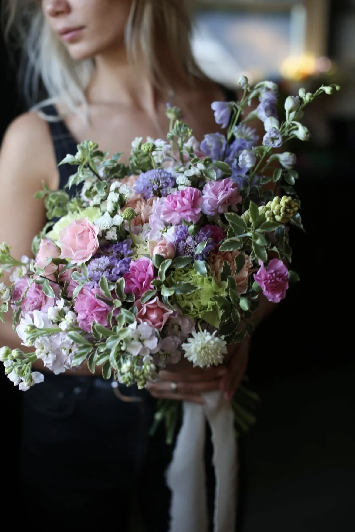 Woman holding a pastel bouquet of pink and purple flowers