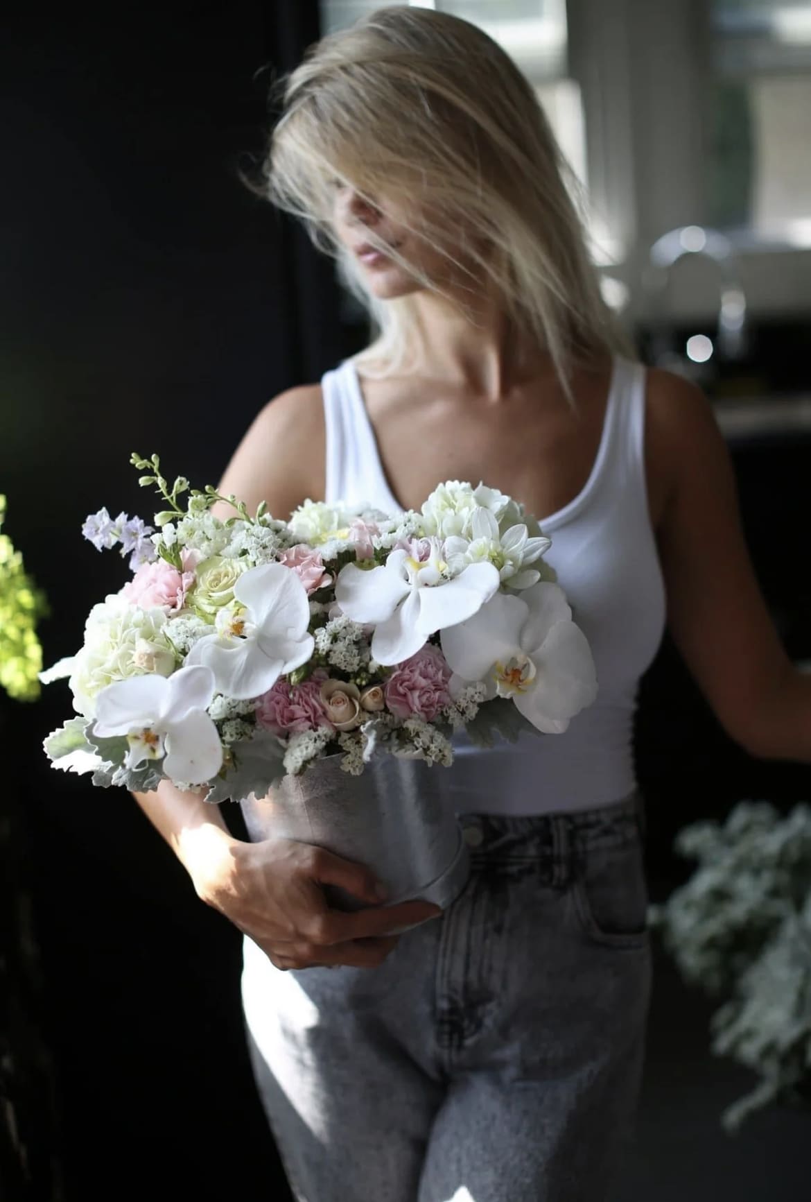 Woman holding a pastel bouquet with white orchids and pink roses