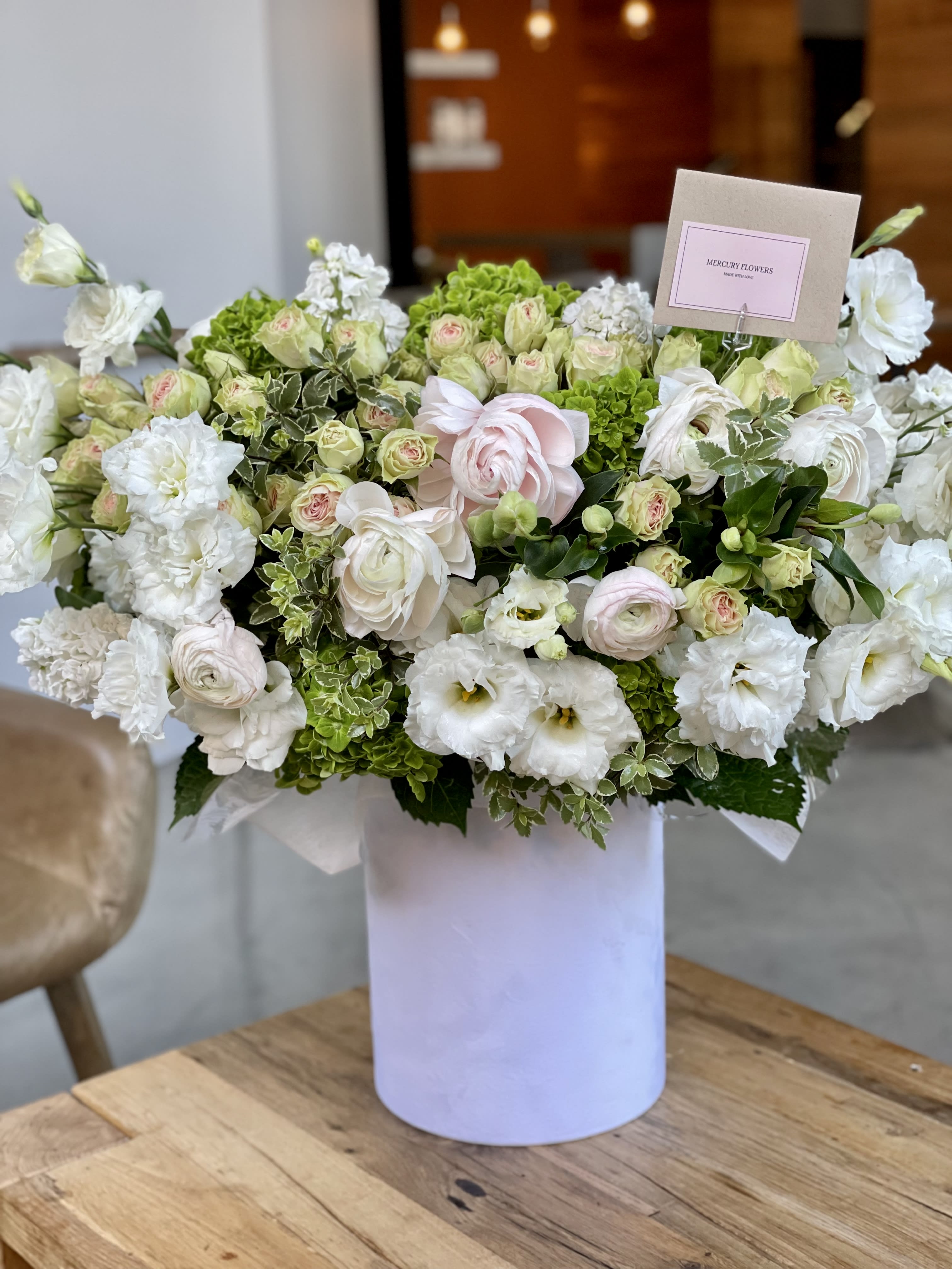 Large white and pale pink flower arrangement in a white box