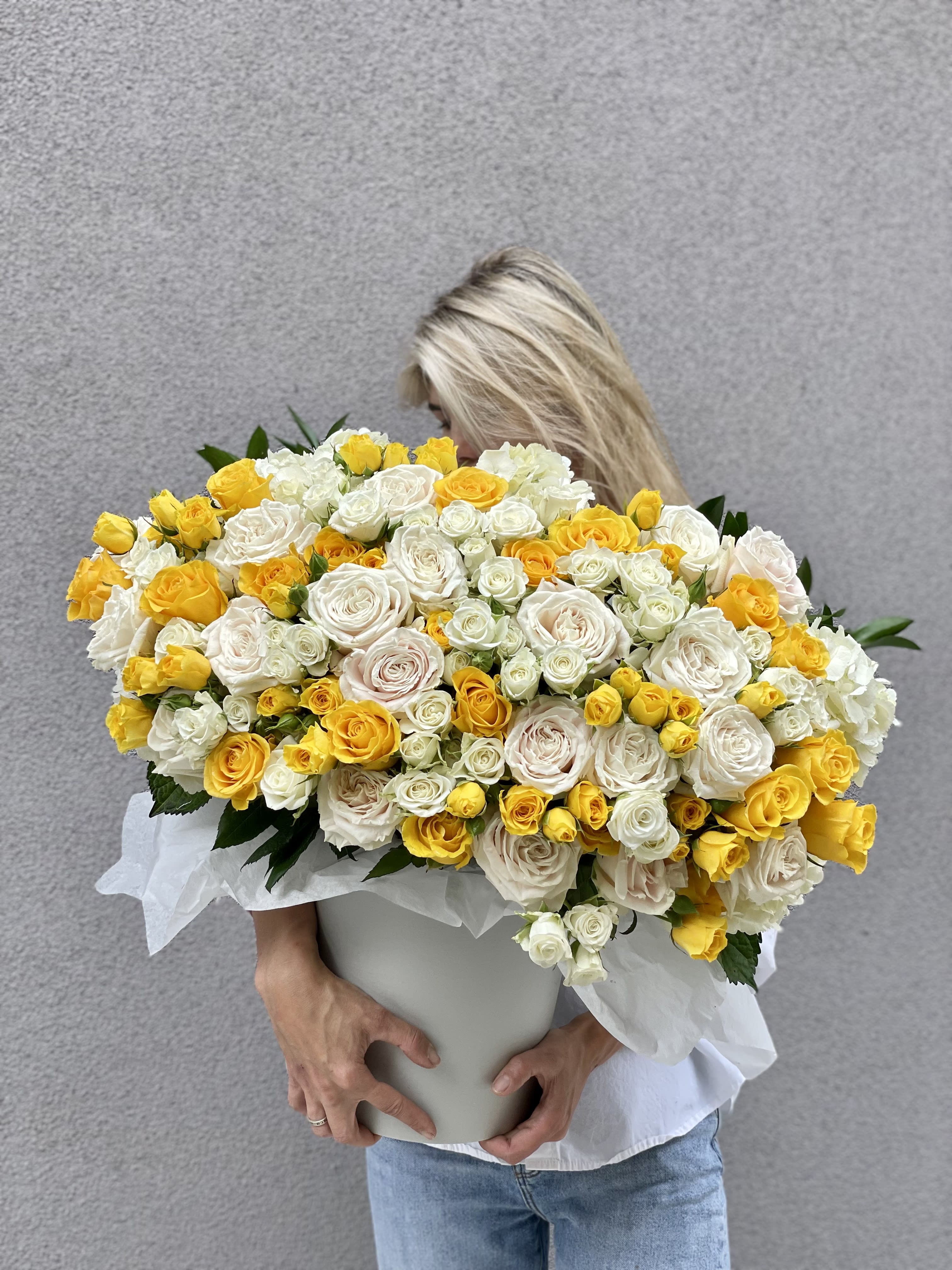 Large bouquet of yellow and white roses in a white container