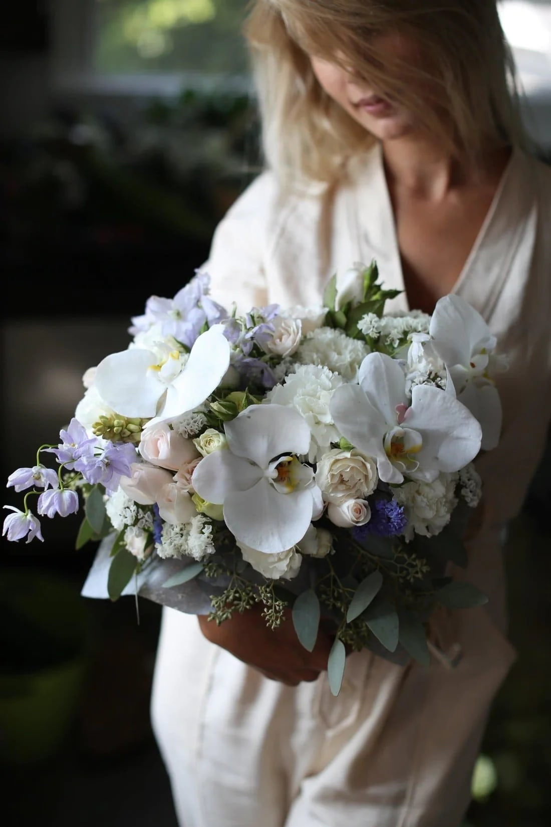 Woman holding a bouquet of white orchids and pale flowers