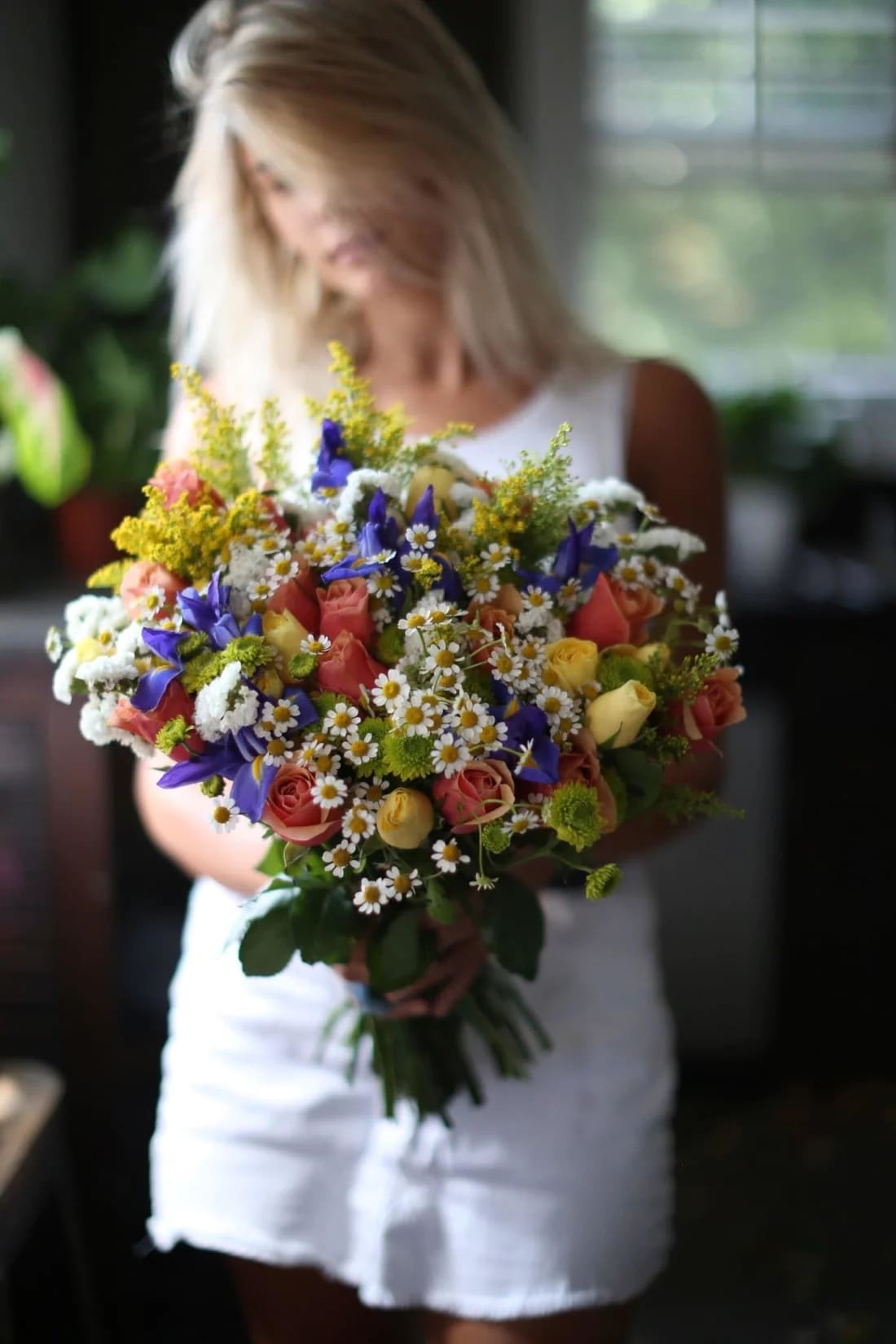 Woman holding a colorful bouquet of roses and daisies