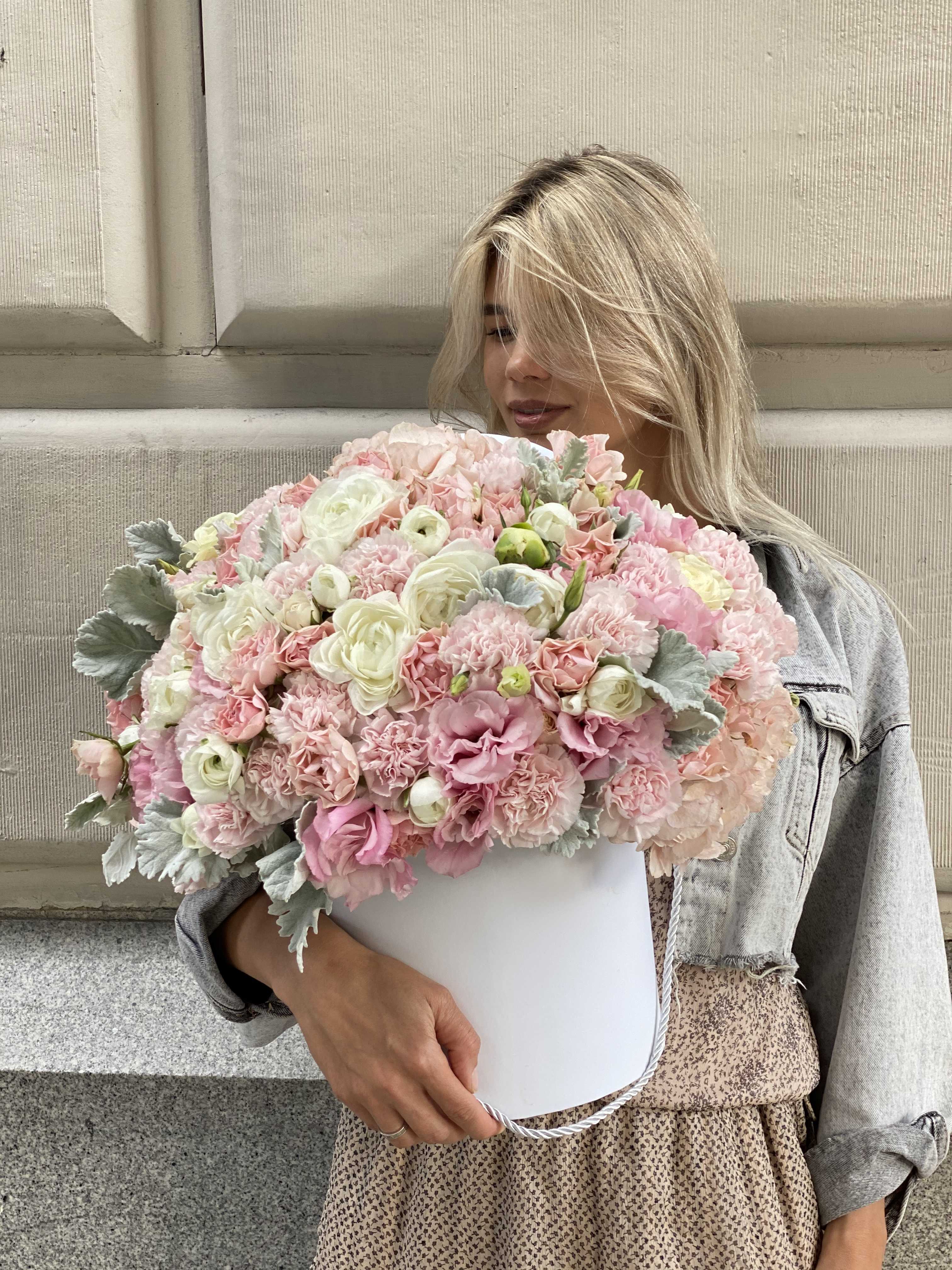 Woman holding a large pastel pink and white bouquet in a white box
