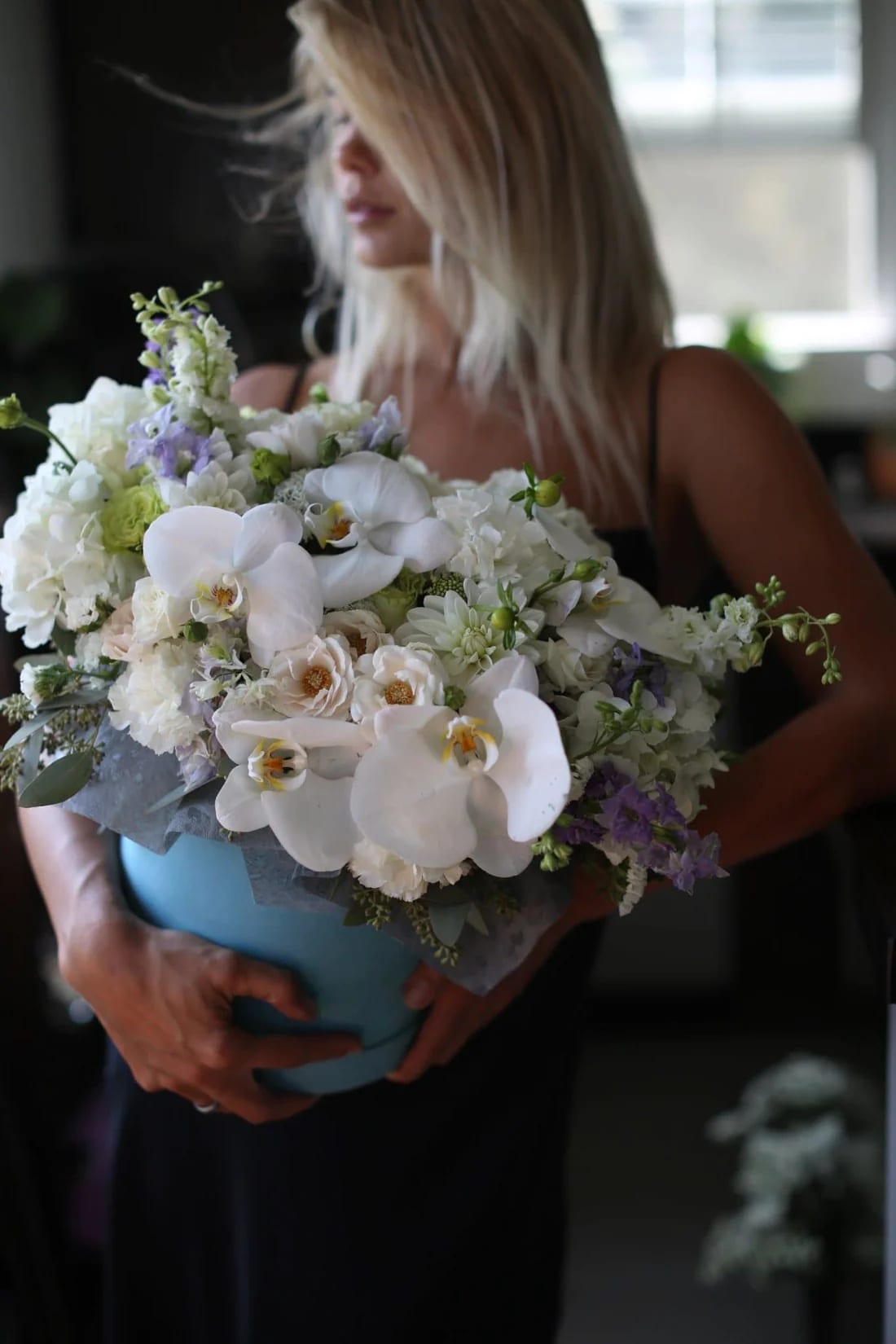 Woman holding a large white and lavender bouquet with orchids