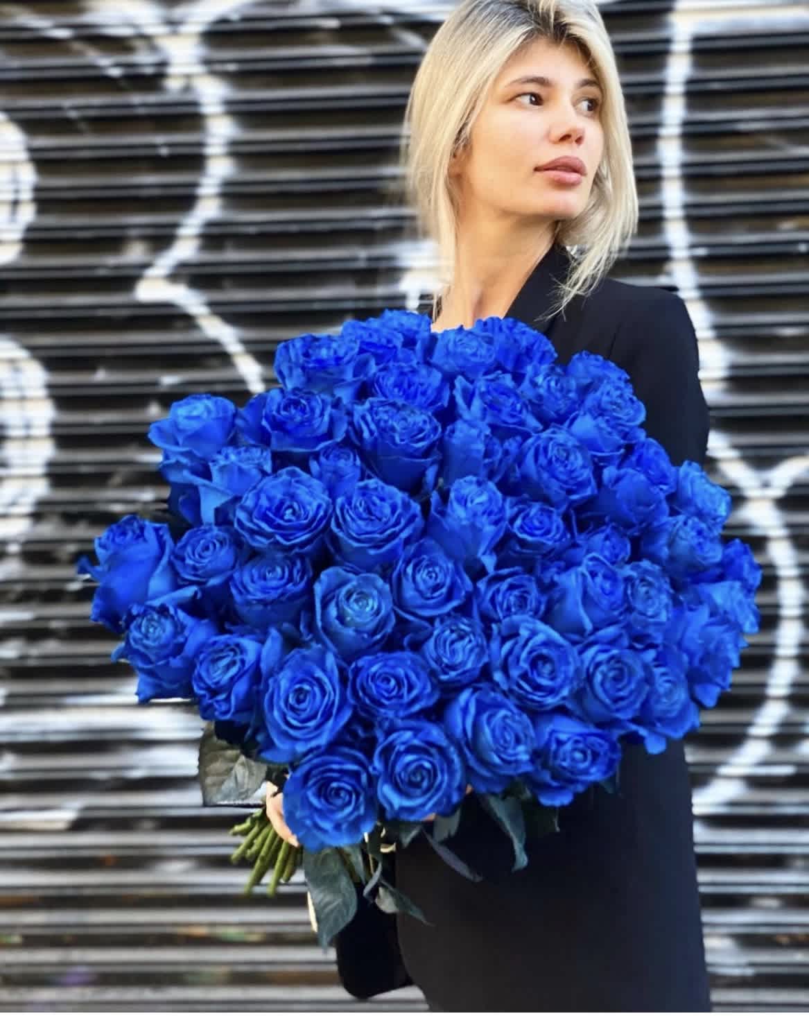 Woman holding a large bouquet of vivid blue roses