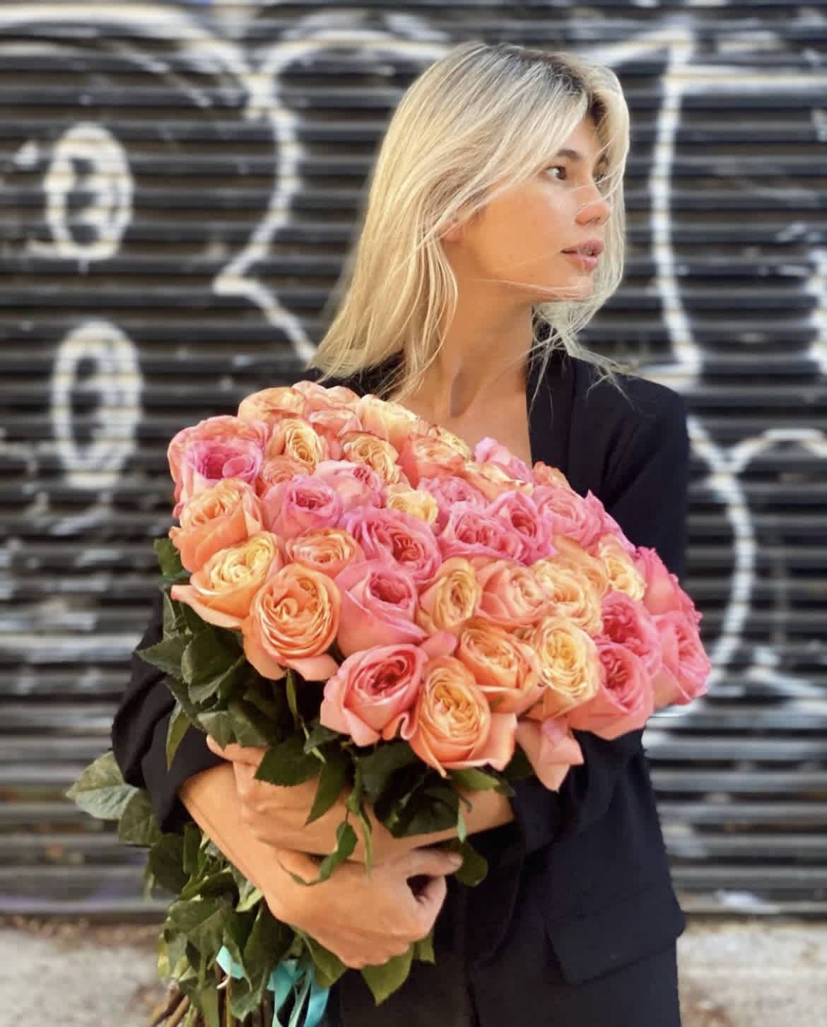 Woman holding a large bouquet of pink and peach roses