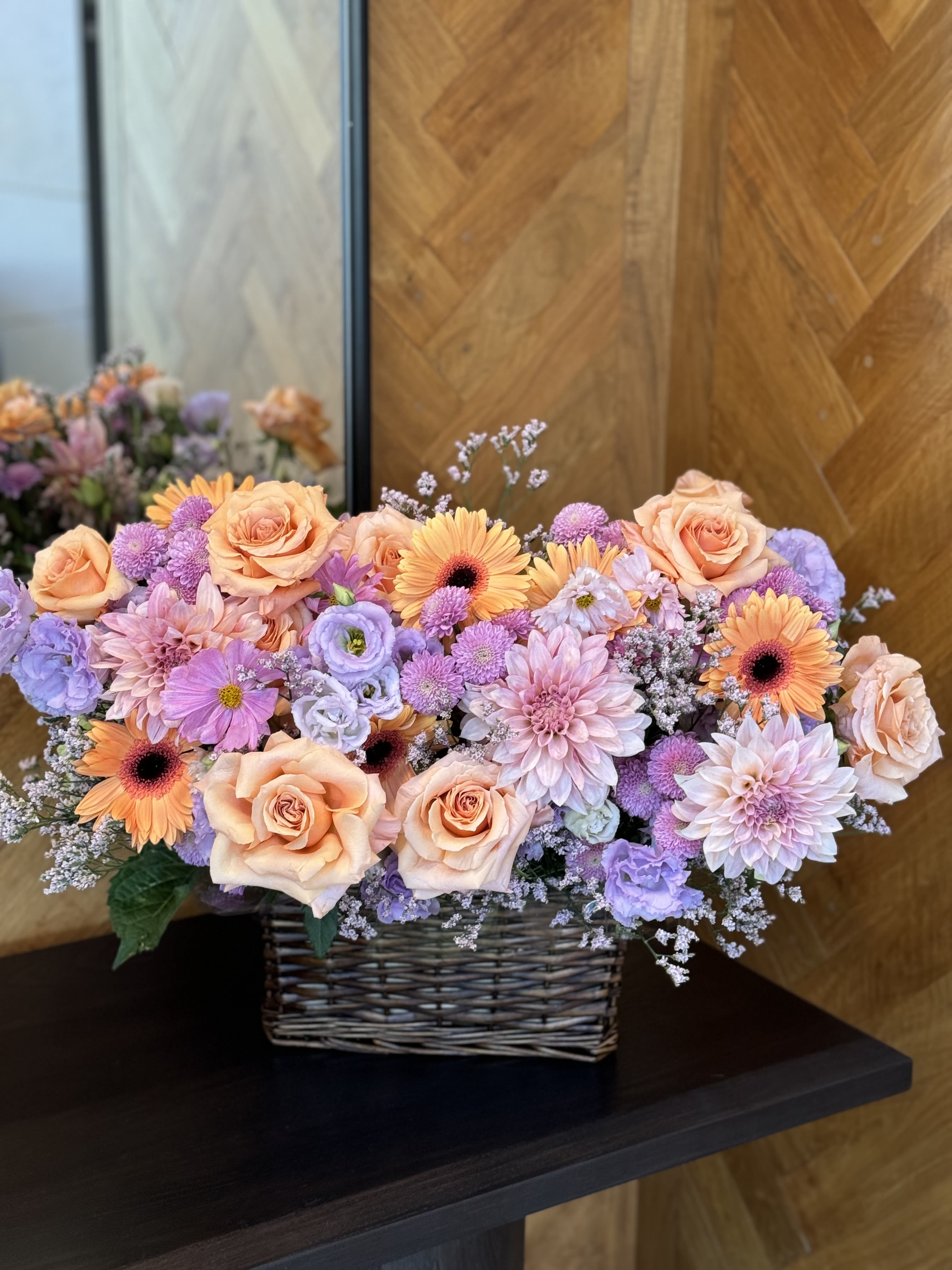 Peach roses and lavender flowers in a wicker basket