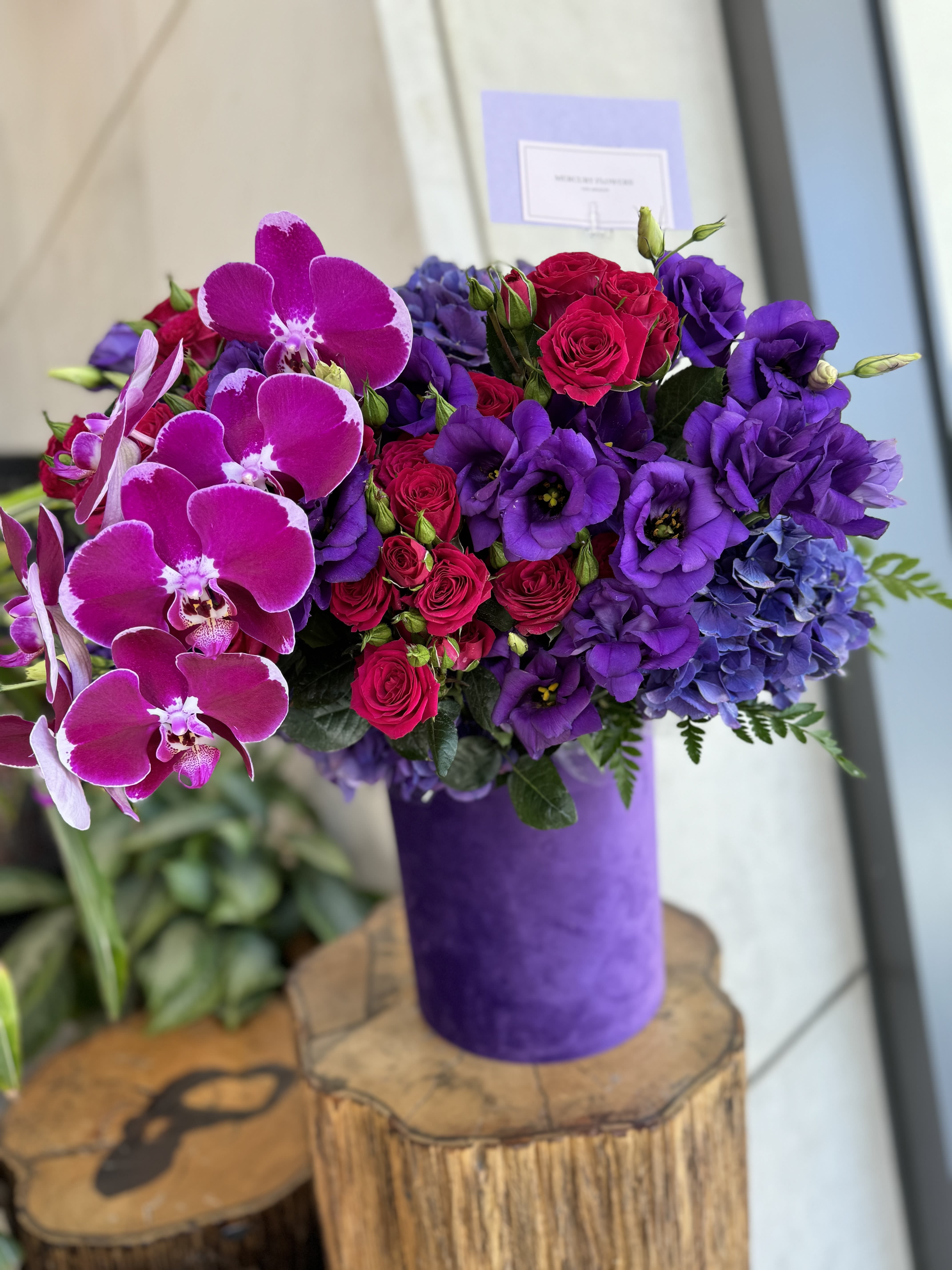 Purple and pink bouquet with orchids, roses, and hydrangeas in a purple vase