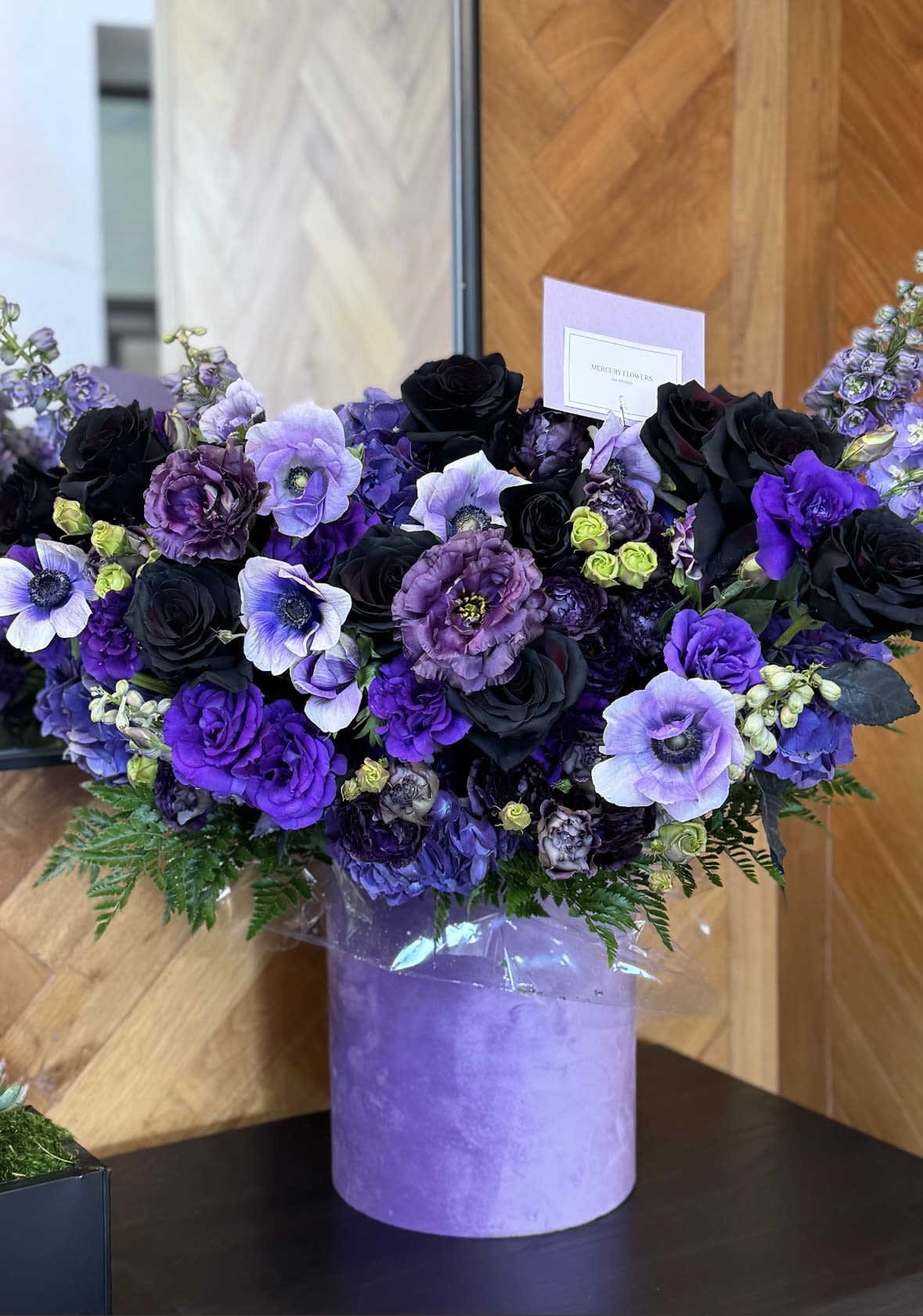Purple and black floral arrangement in a lavender box