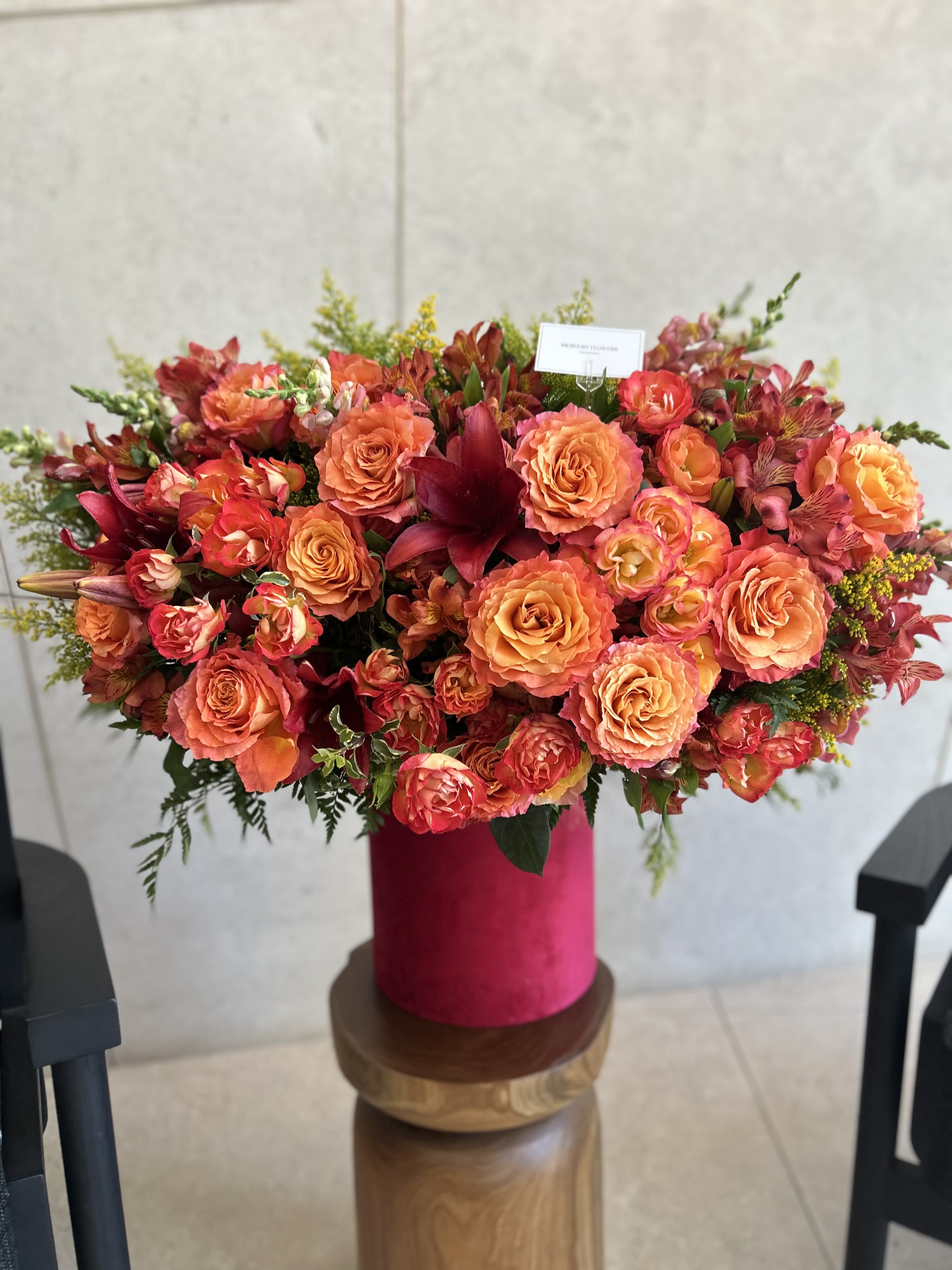 Large orange and pink floral arrangement in a magenta vase