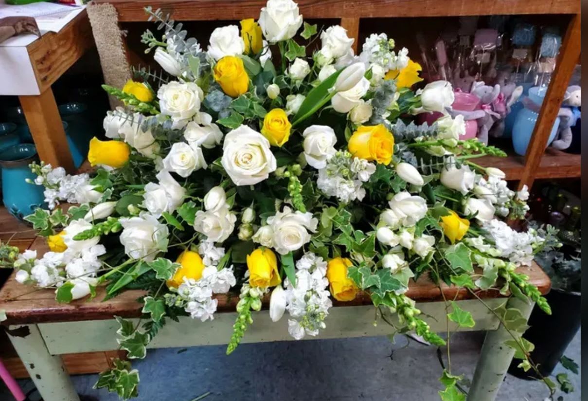 Sun-Kissed Memories Casket Spray - Designed to celebrate a life filled with love and treasured moments. Sunny yellow roses symbolize friendship, joy, and the bright spirit of a loved one shared, while pure white roses represent peace, honor, and everlasting remembrance.  
