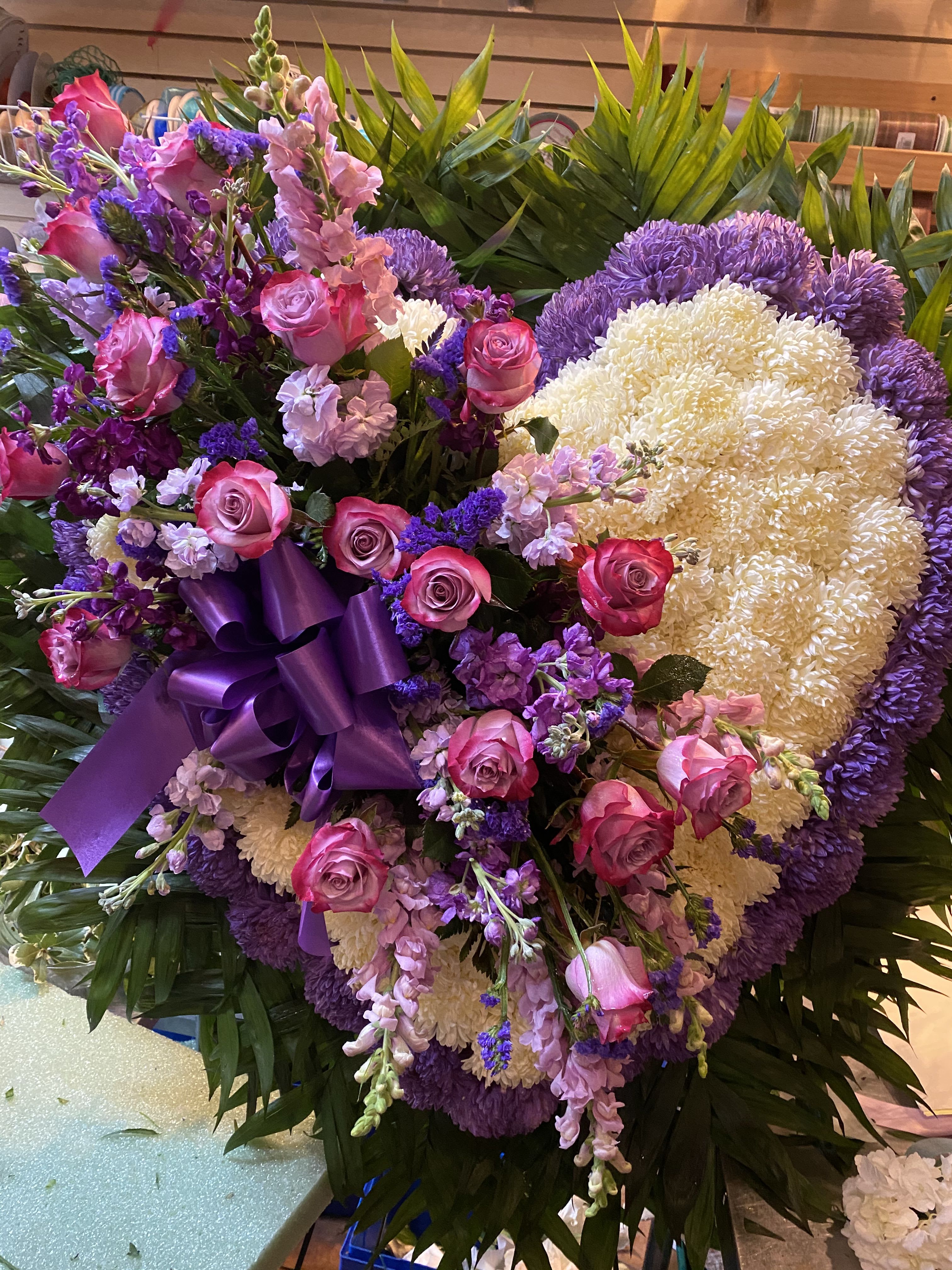 Large purple and pink floral standing arrangement with a ribbon bow
