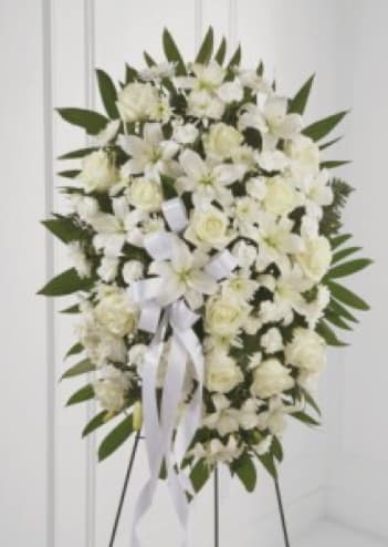 White floral standing spray with ribbon on an easel