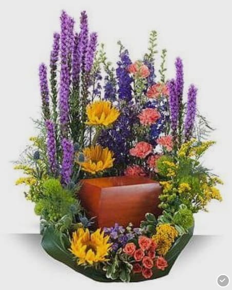 Tall mixed floral arrangement with purple spikes, yellow blooms, and coral flowers in a wooden container