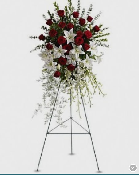 Standing floral spray with red roses and white lilies on a metal easel