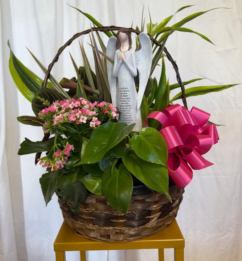 Basket of pink flowers with an angel figurine and bright ribbon