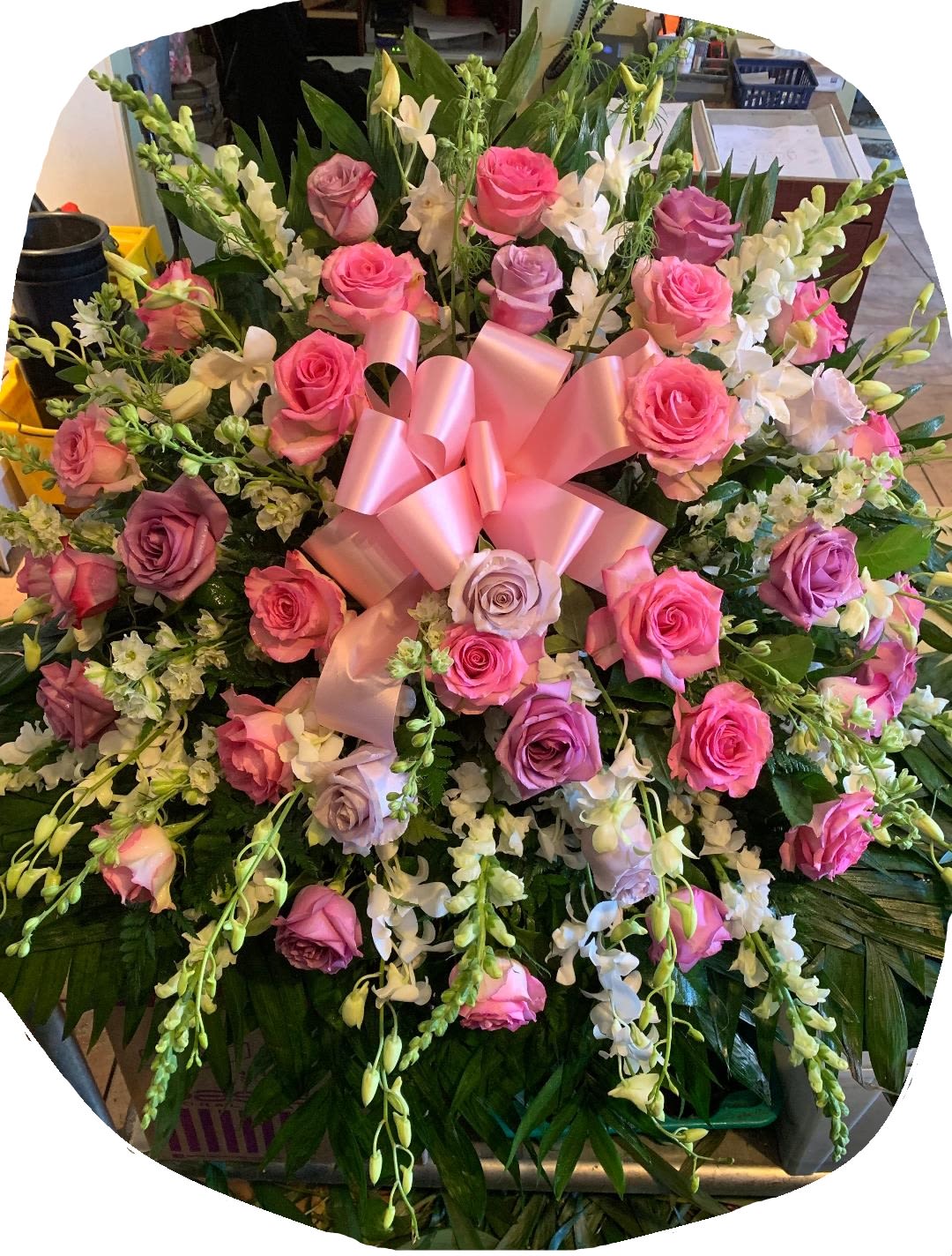Large bouquet of pink and lavender roses with white orchids and a pink ribbon