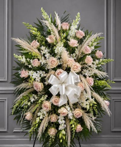 Standing floral spray with pale pink roses, white flowers, and a white bow