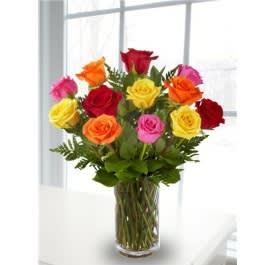 Mixed-color roses arranged in a clear glass vase on a white table
