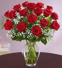 Arrangement of red roses with white filler flowers in a clear glass vase on a table