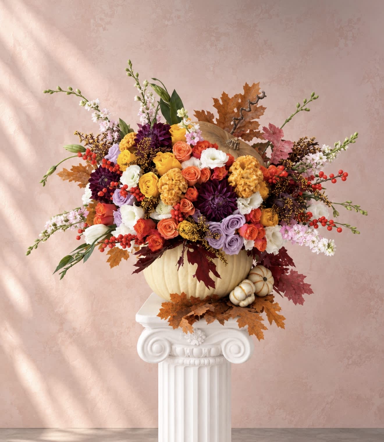 Colorful floral arrangement in a pumpkin vase with autumn leaves