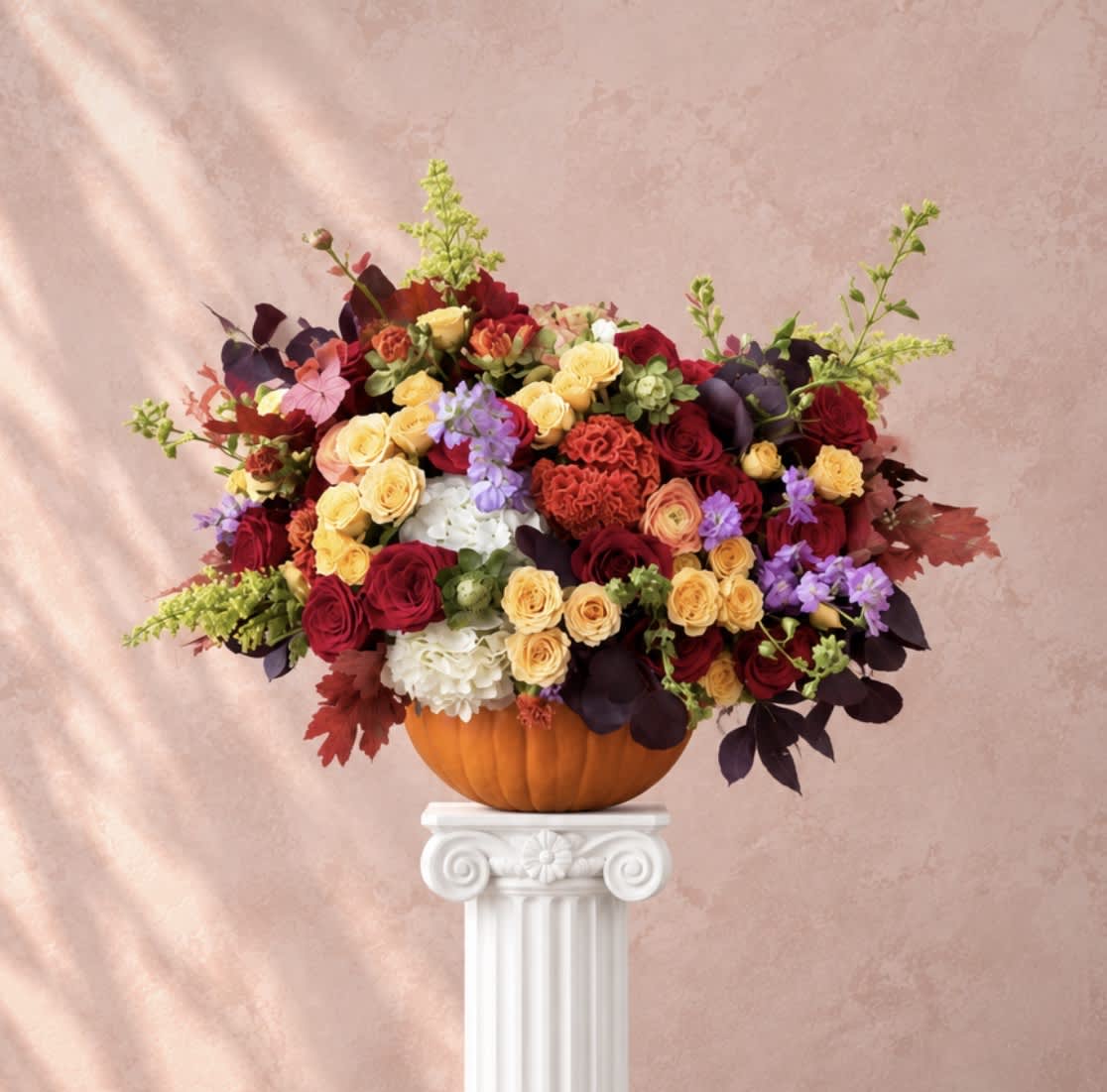 Mixed roses and hydrangeas arranged in a pumpkin vase