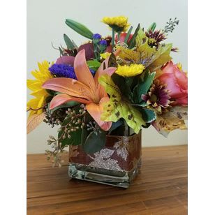 Mixed bouquet in a square glass vase with lilies and bright blooms
