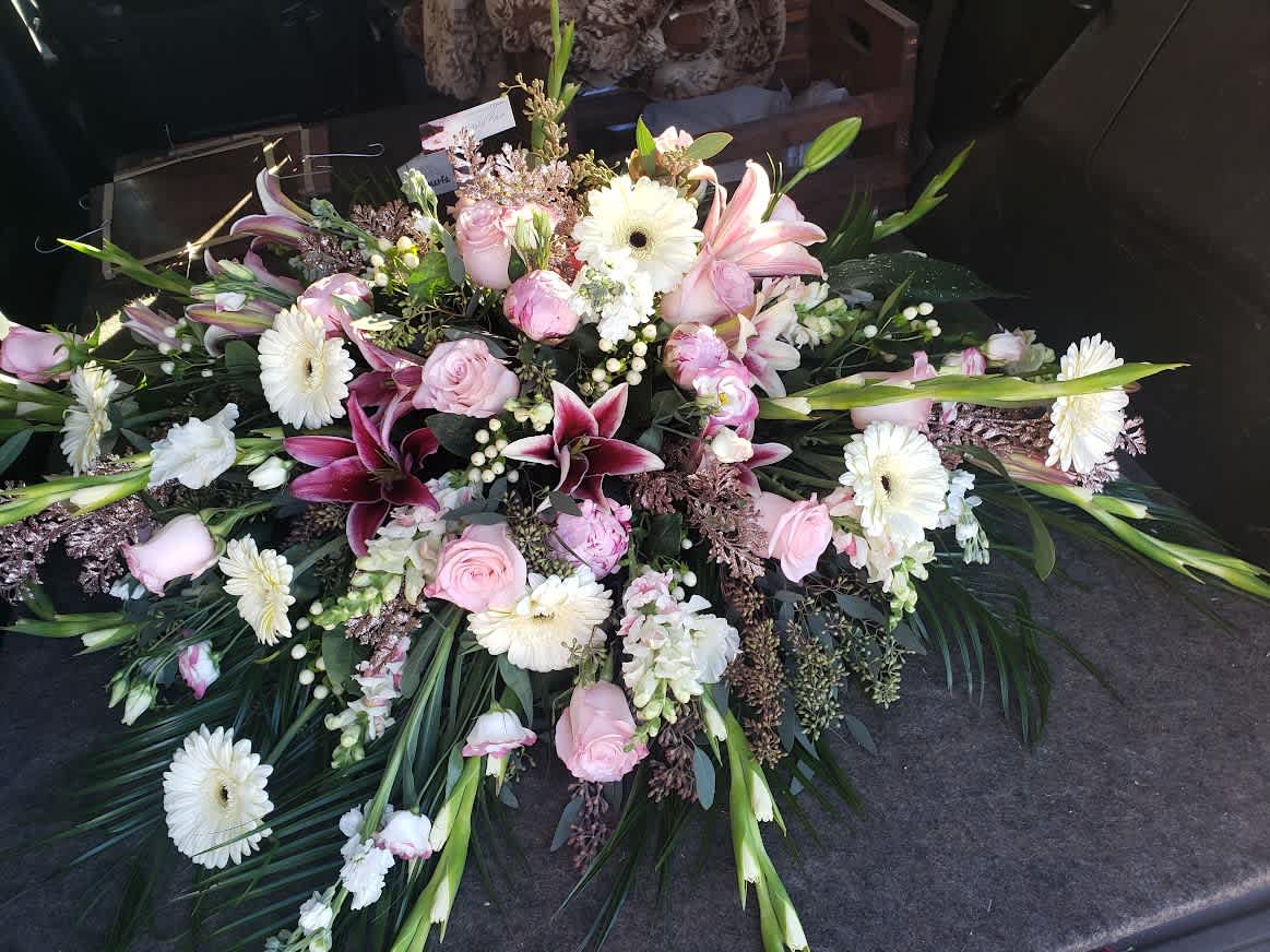 Large pink and white floral casket spray with lilies and daisies