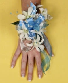White flower corsage with blue ribbon on a hand