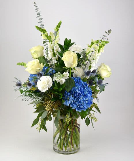 Blue and white floral arrangement in a clear glass vase