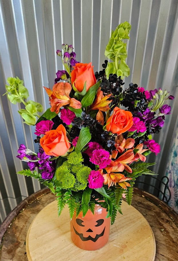 Jack o Flowers - Bring the fun and color of Halloween to life with Jack O’ Flowers, a lively fall bouquet bursting with personality! This festive arrangement features vibrant orange roses, playful purple blooms, lime green accents, and bold seasonal foliage, all hand-designed in a charming jack-o’-lantern vase that adds a touch of Halloween spirit to any space. Perfect for Halloween parties, autumn birthdays, or spooky-season décor, Jack O’ Flowers combines classic fall colors with a fresh, modern twist. Each bouquet is handcrafted by our local florist in Omaha and available for same-day flower delivery ( IF ORDERED BY 12 NOON CENTRAL TIME) to make your celebration extra special. Perfect for: Halloween décor or gifts Fall celebrations &amp; parties Brightening a home or office A fun seasonal surprise