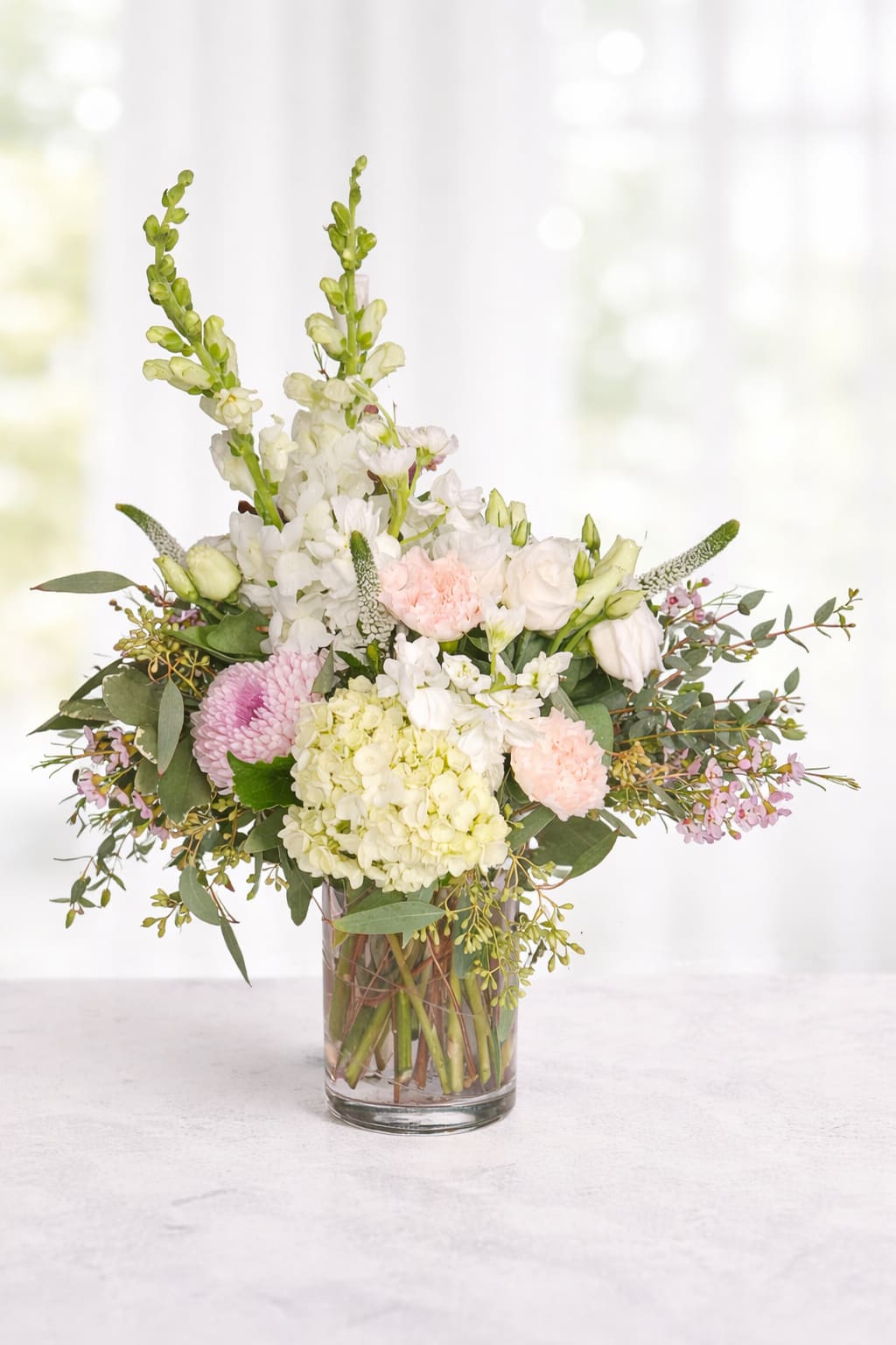 Pastel flower arrangement in a clear glass vase with white and pink blooms
