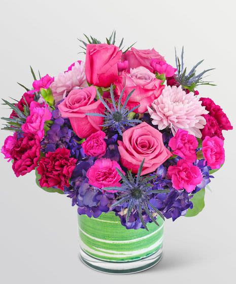 Pink roses and carnations with purple hydrangeas in a green striped vase
